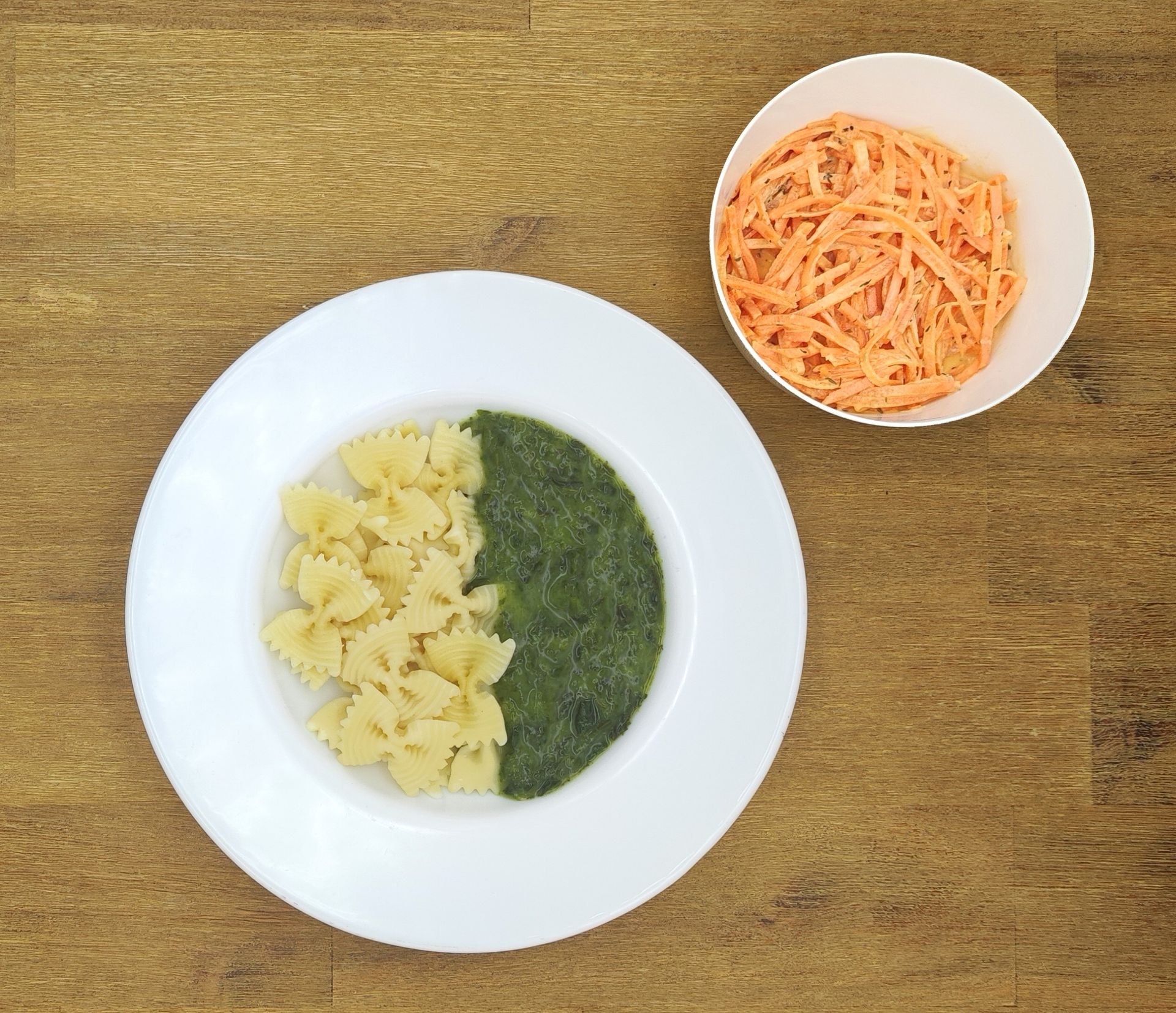 Auf einem weißen Teller mit Apfelmus lagen Crêpes auf einem Holztisch.