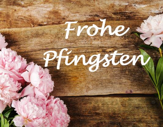 „Frohe Pfingsten“-Schriftzug auf rustikalem Holzgrund mit rosa Pfingstrosen.