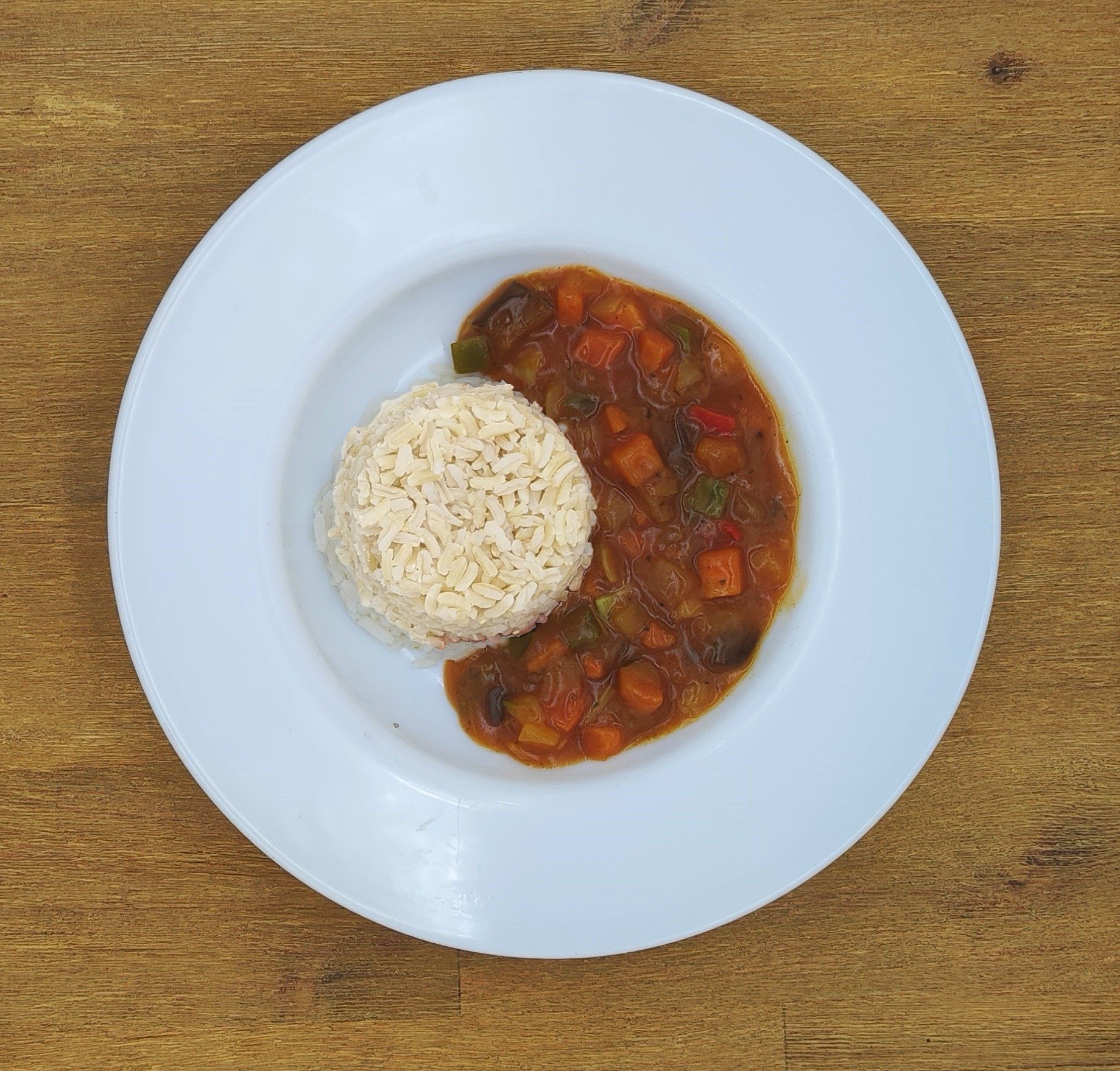 Auf einem weißen Teller mit Apfelmus lagen Crêpes auf einem Holztisch.