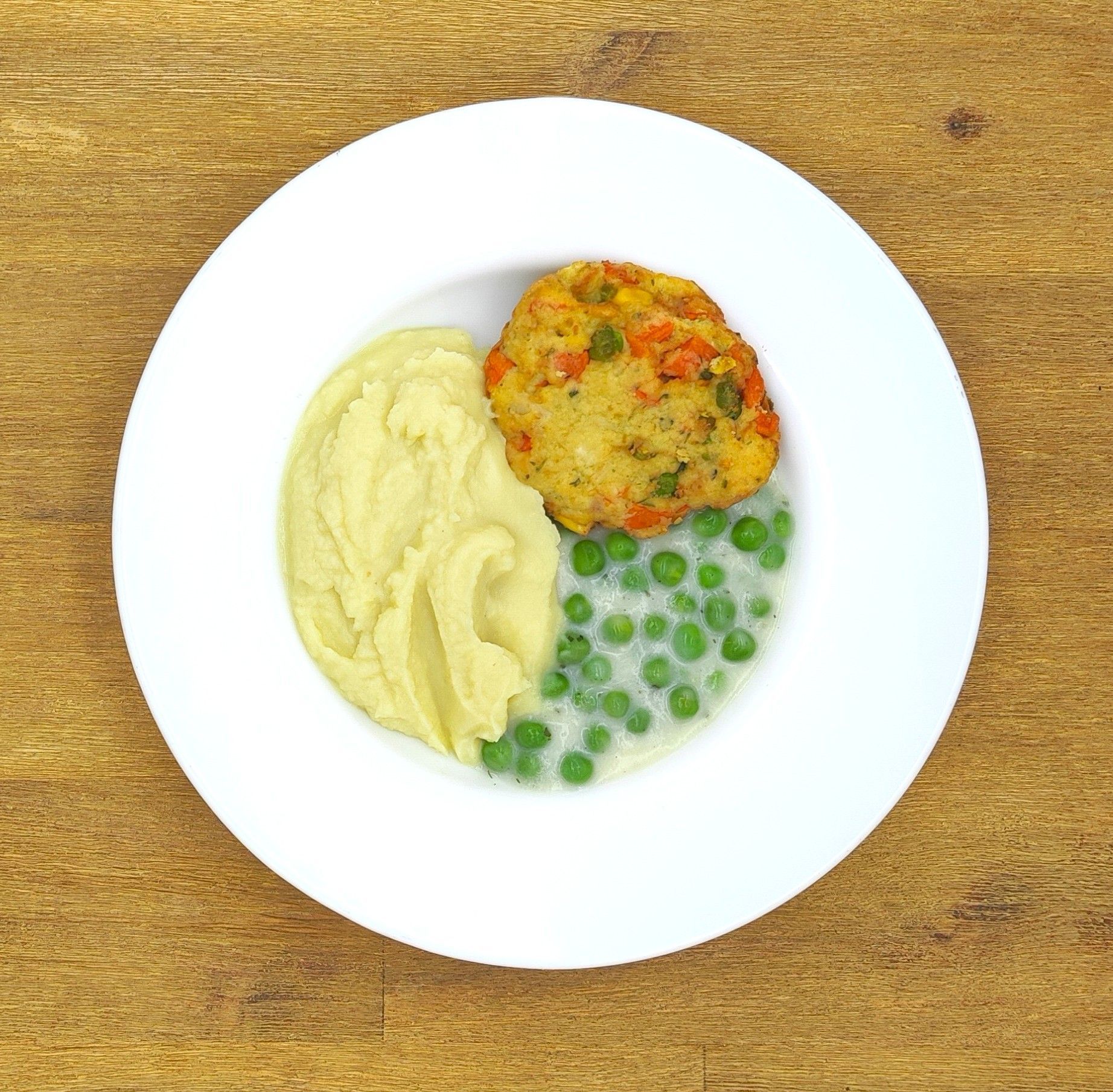 Auf dem Teller befanden sich: Kartoffelpüree, Erbsen in Soße und ein Gemüsebratling.
