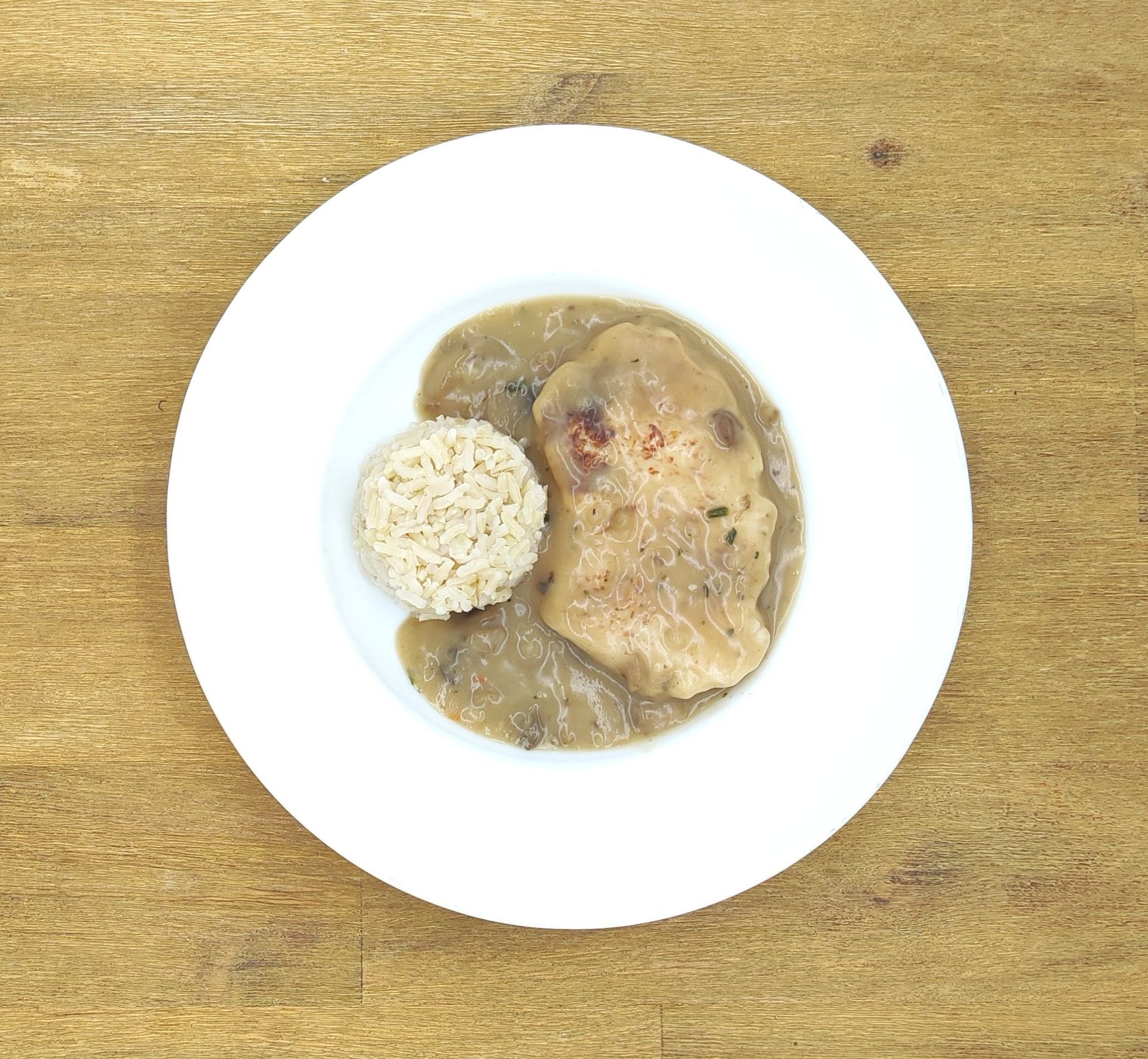 Ein Teller Schweinekotelett mit Pilzsoße und einer Portion Reis.