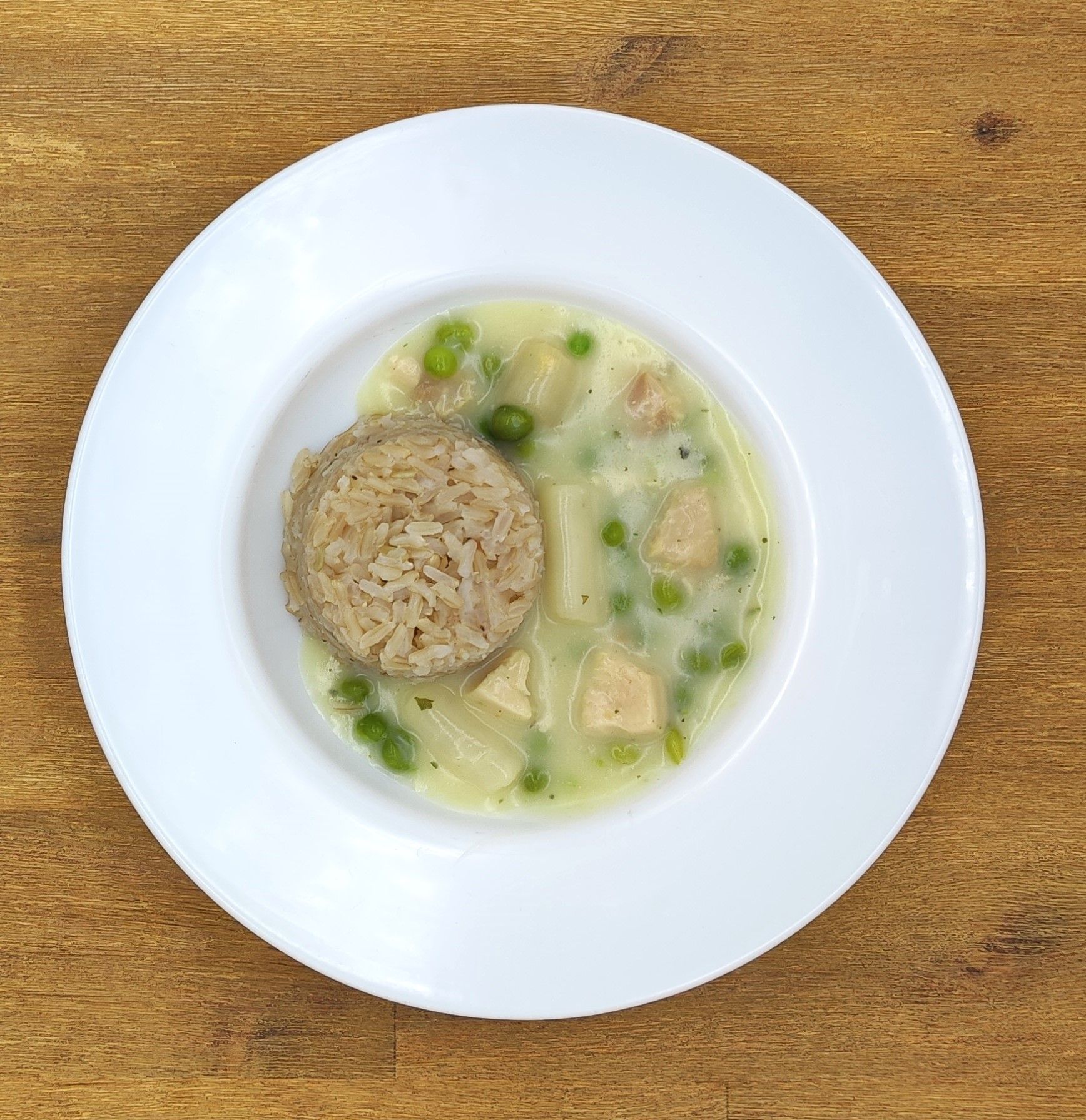 Weißer Teller mit Eintopf und einer Portion Reis.