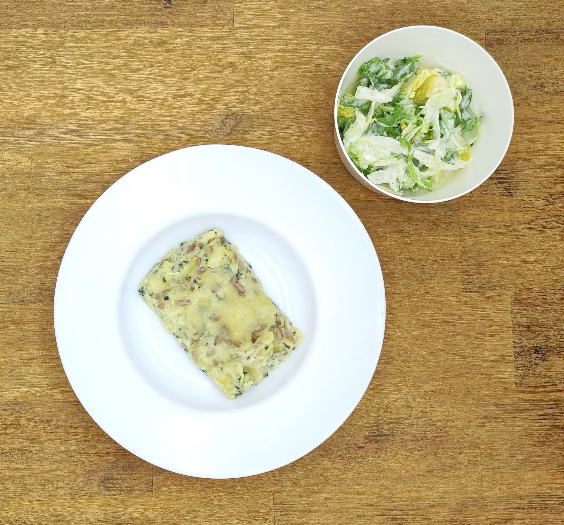 Weiße Schüssel mit Linsensuppe und Brot auf einer Holzoberfläche.