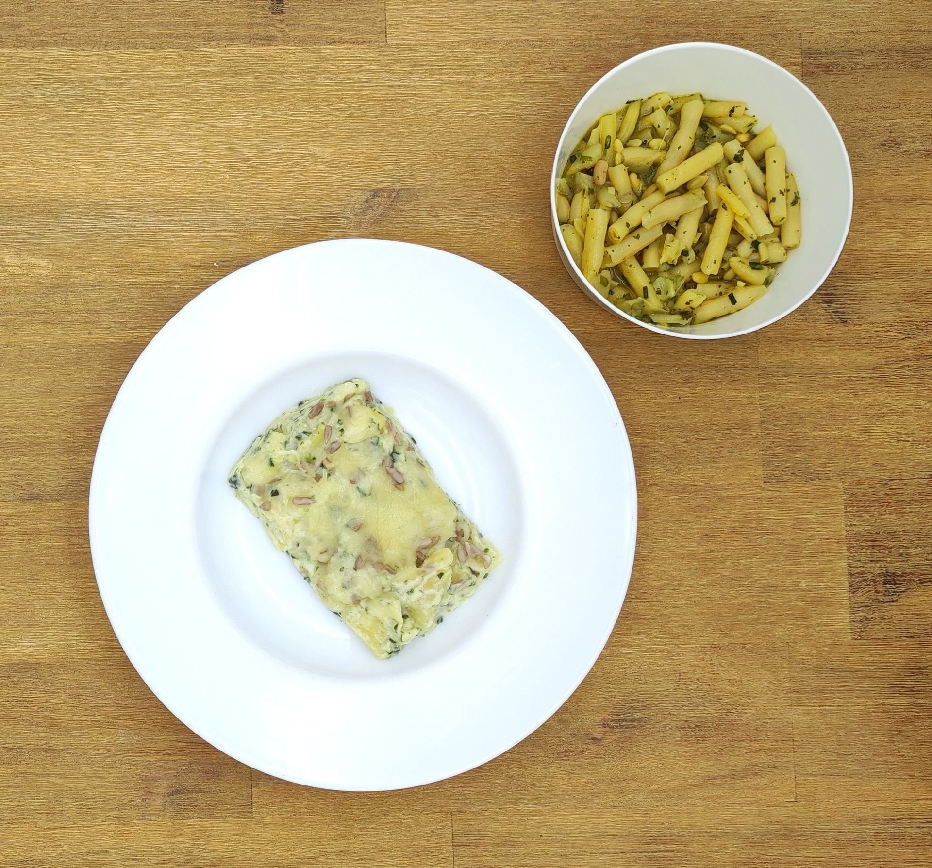 Weißer Teller mit Farfalle-Nudeln und Orangensauce, bestreut mit geriebenem Käse.