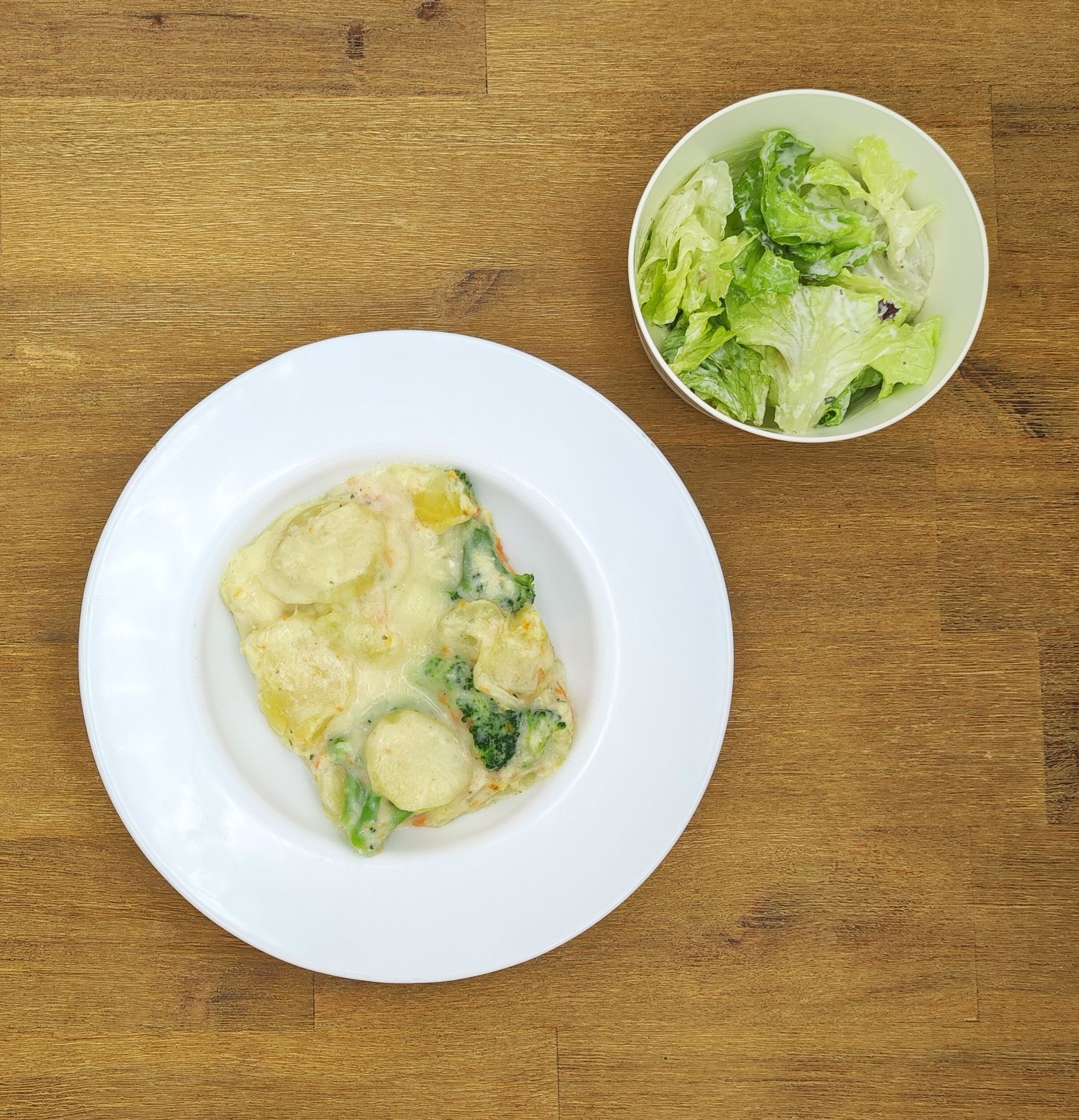 Omelett und Salat auf einem Holztisch. Das Omelett enthält Gemüse, der Salat besteht aus grünem Salat.