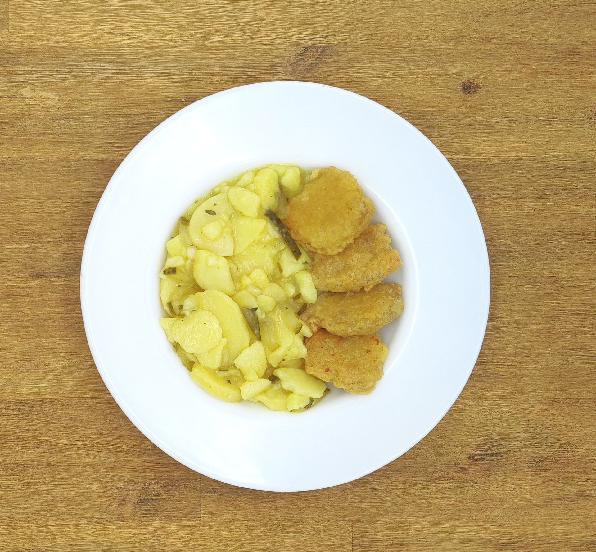 Auf einem weißen Teller mit Apfelmus lagen Crêpes auf einem Holztisch.