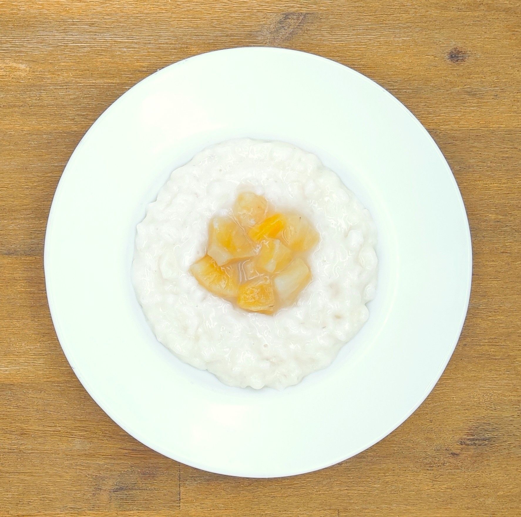 Weiße Schüssel mit Linsensuppe und Brot auf einer Holzoberfläche.