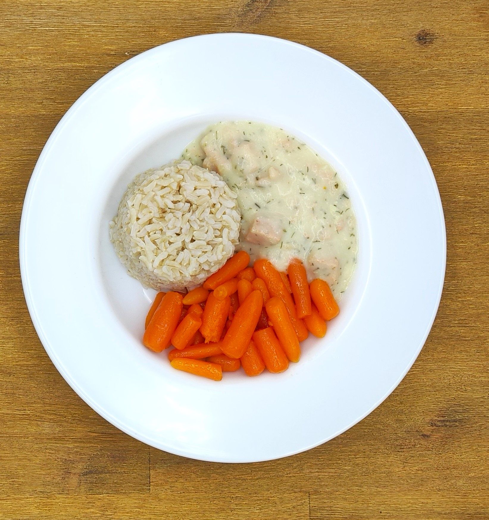 Tellergericht: Hähnchen in cremiger Soße, Reis und Karotten.