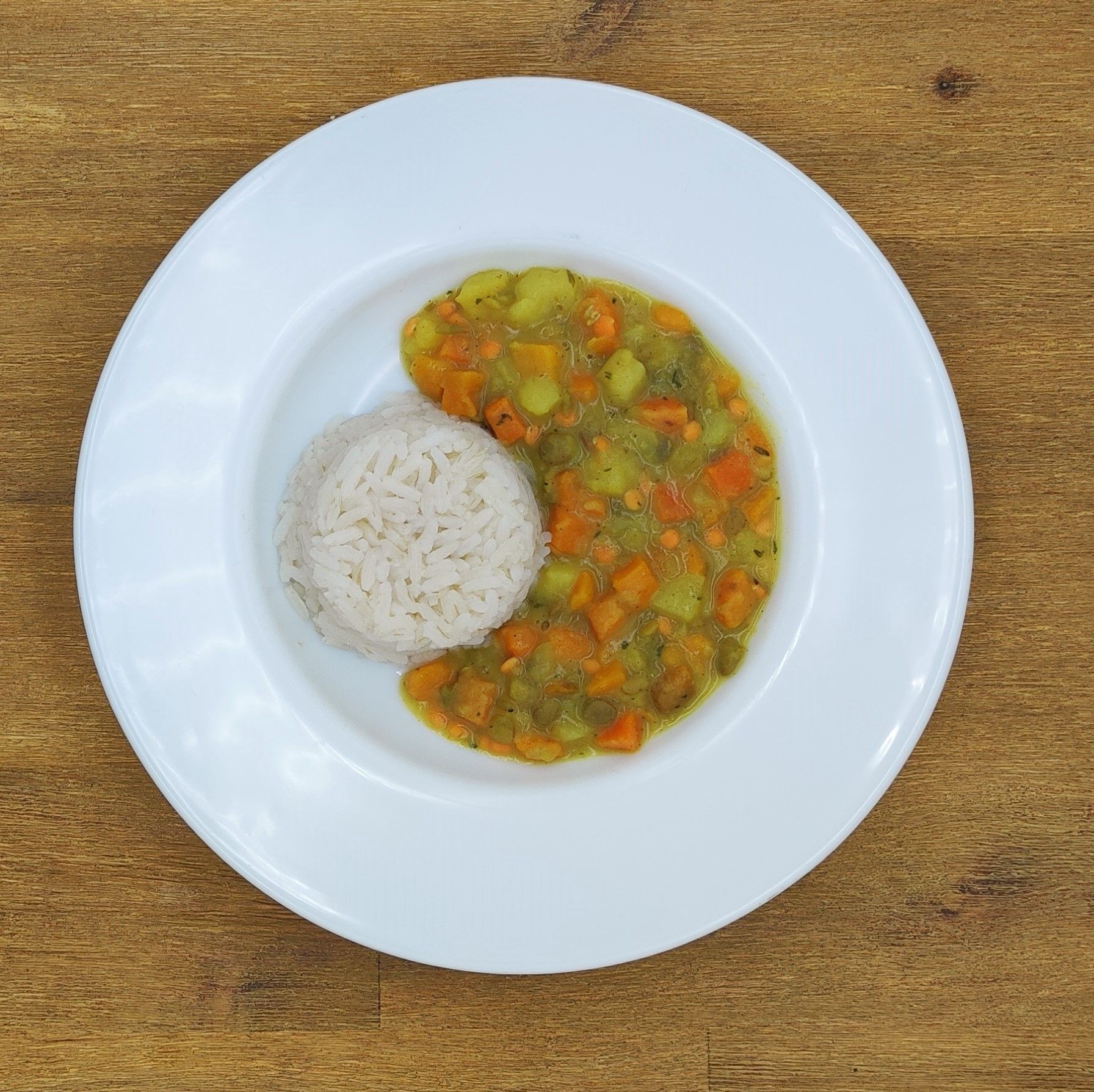 Weißer Teller mit gekochtem Reis und Gemüsebeilage.