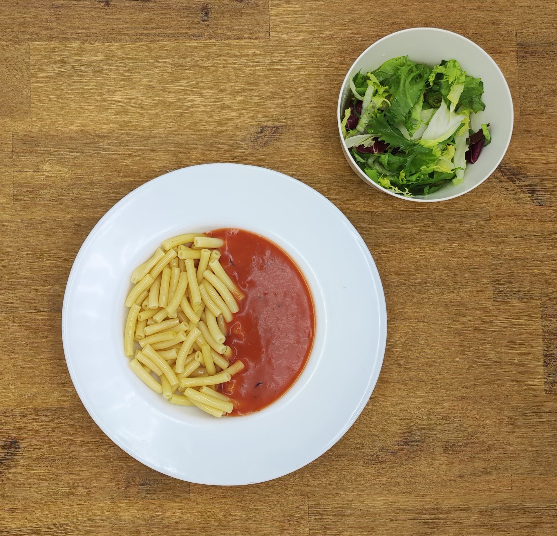 Auf einem weißen Teller mit Apfelmus lagen Crêpes auf einem Holztisch.