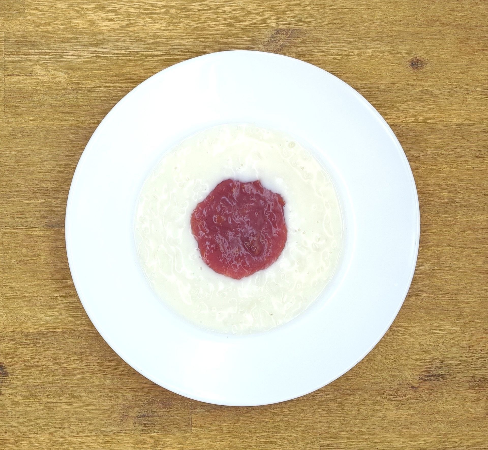 Weißer Teller mit Reis und einem Klecks roter Soße in der Mitte.