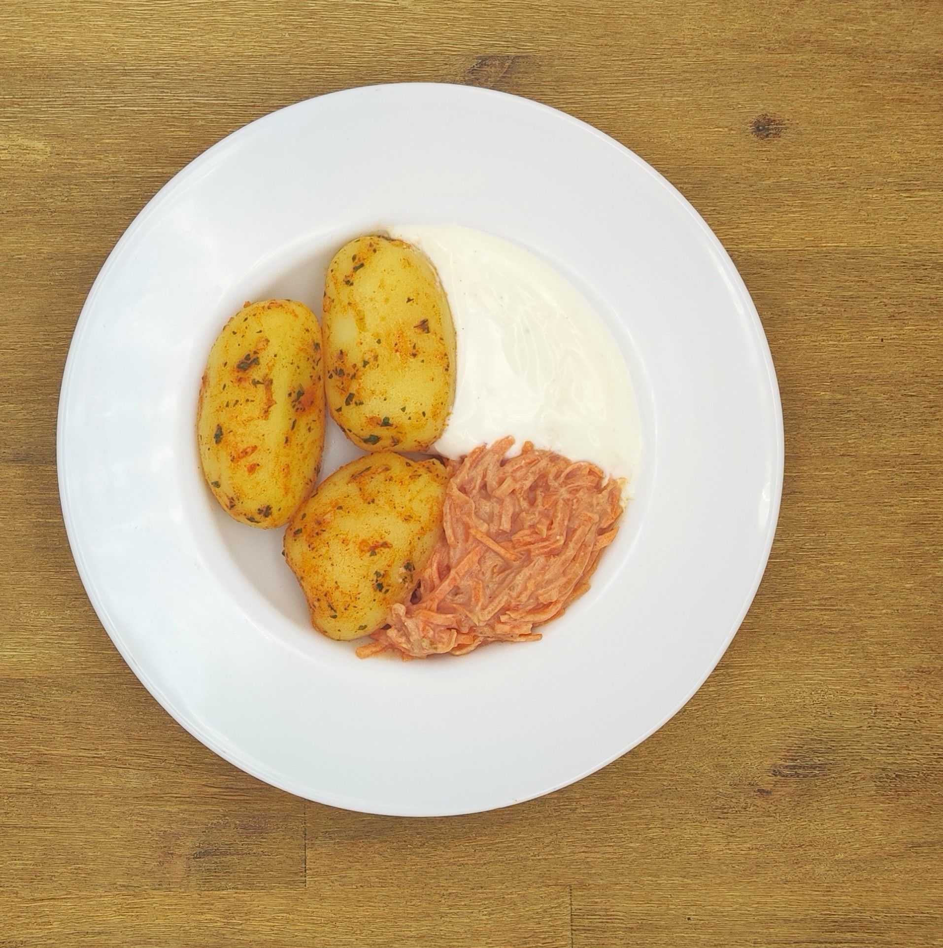 Teller mit Bratkartoffeln, einer weißen Soße und gezupftem Fleisch.