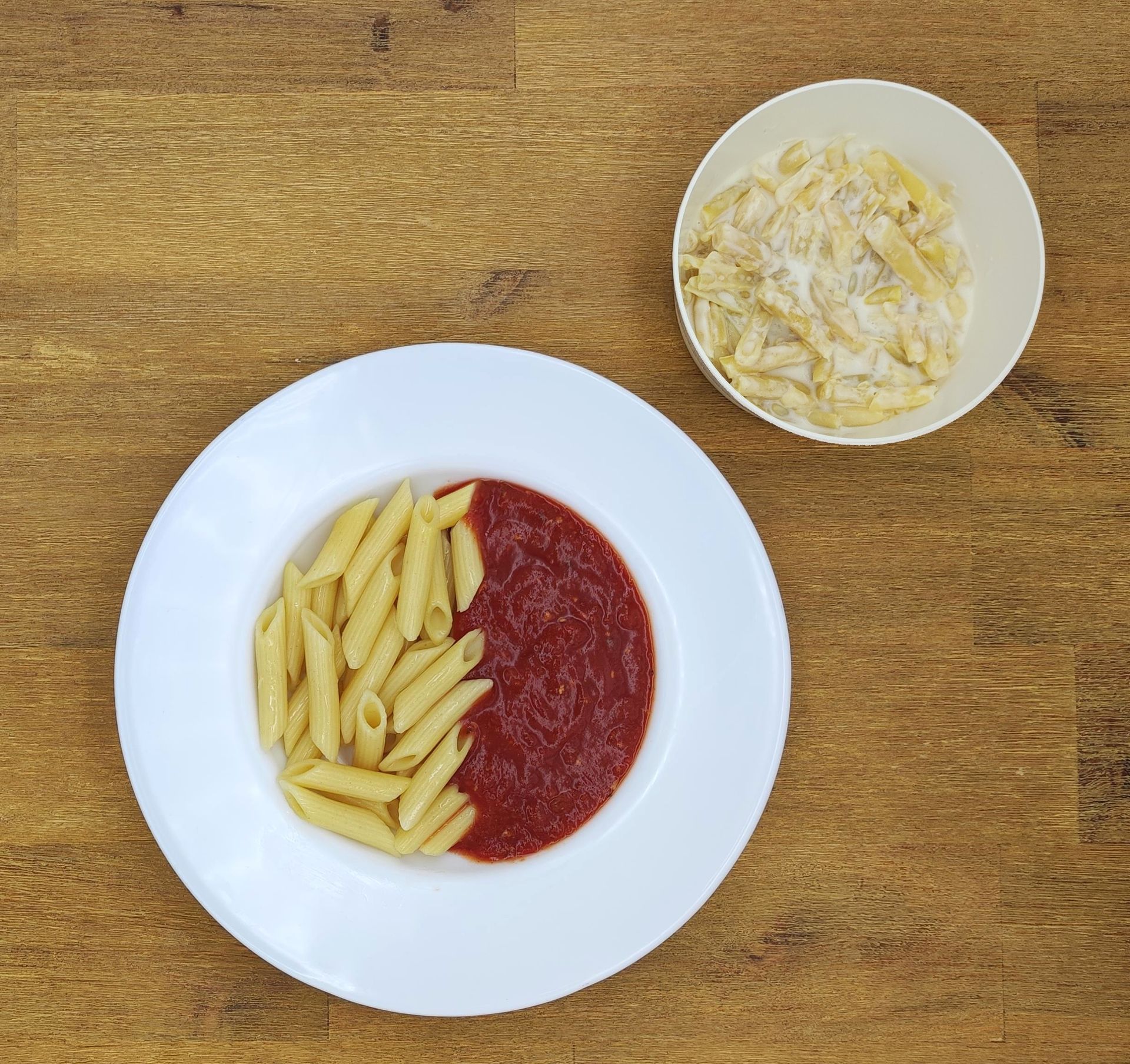 Weißer Teller mit Farfalle-Nudeln und Orangensauce, bestreut mit geriebenem Käse.