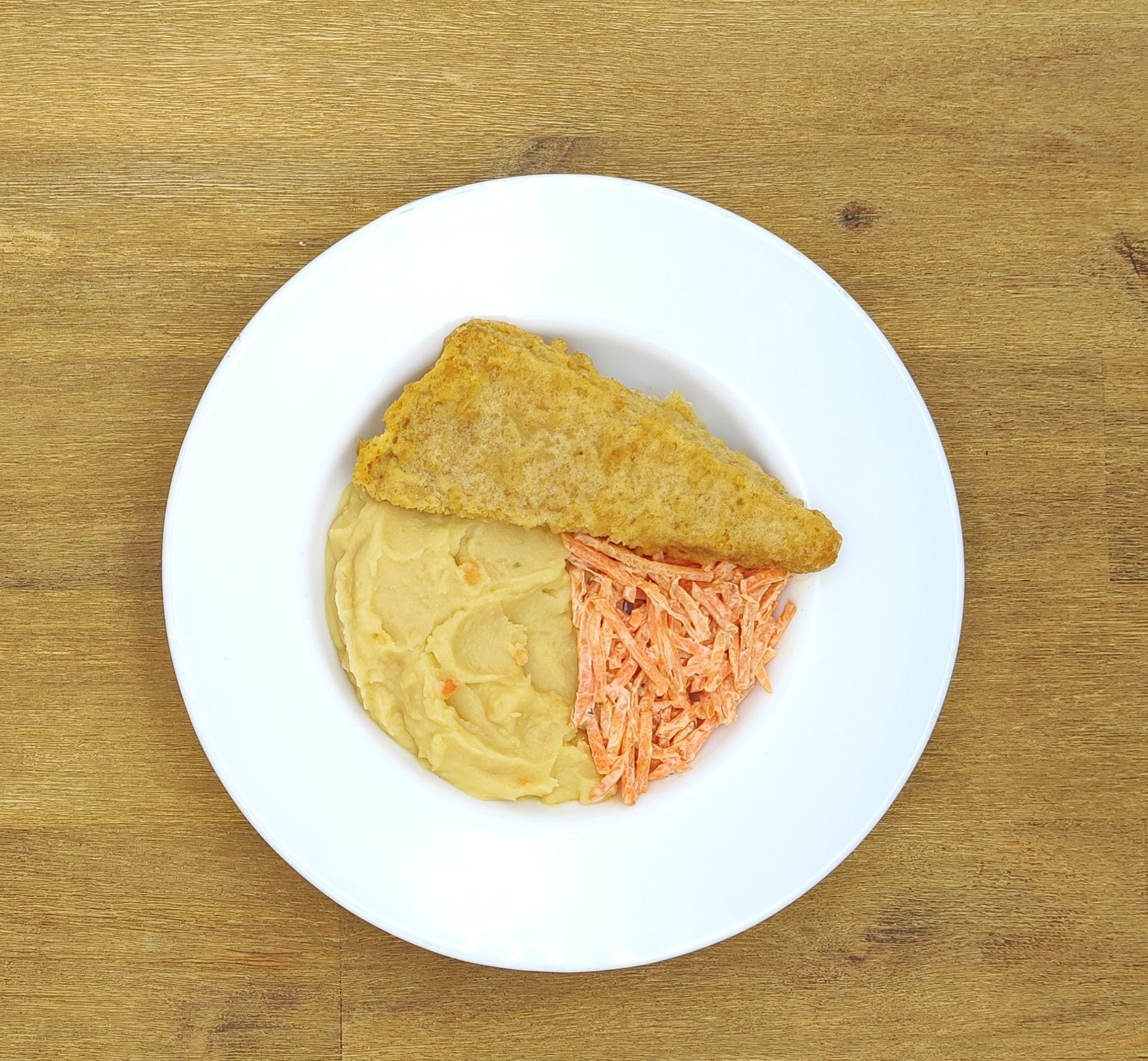 Auf einem weißen Teller mit Apfelmus lagen Crêpes auf einem Holztisch.