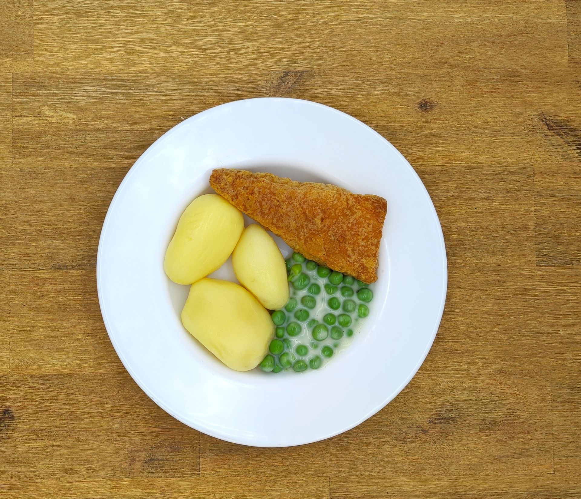 Teller mit einem panierten Fischfilet, Salzkartoffeln und Erbsen.