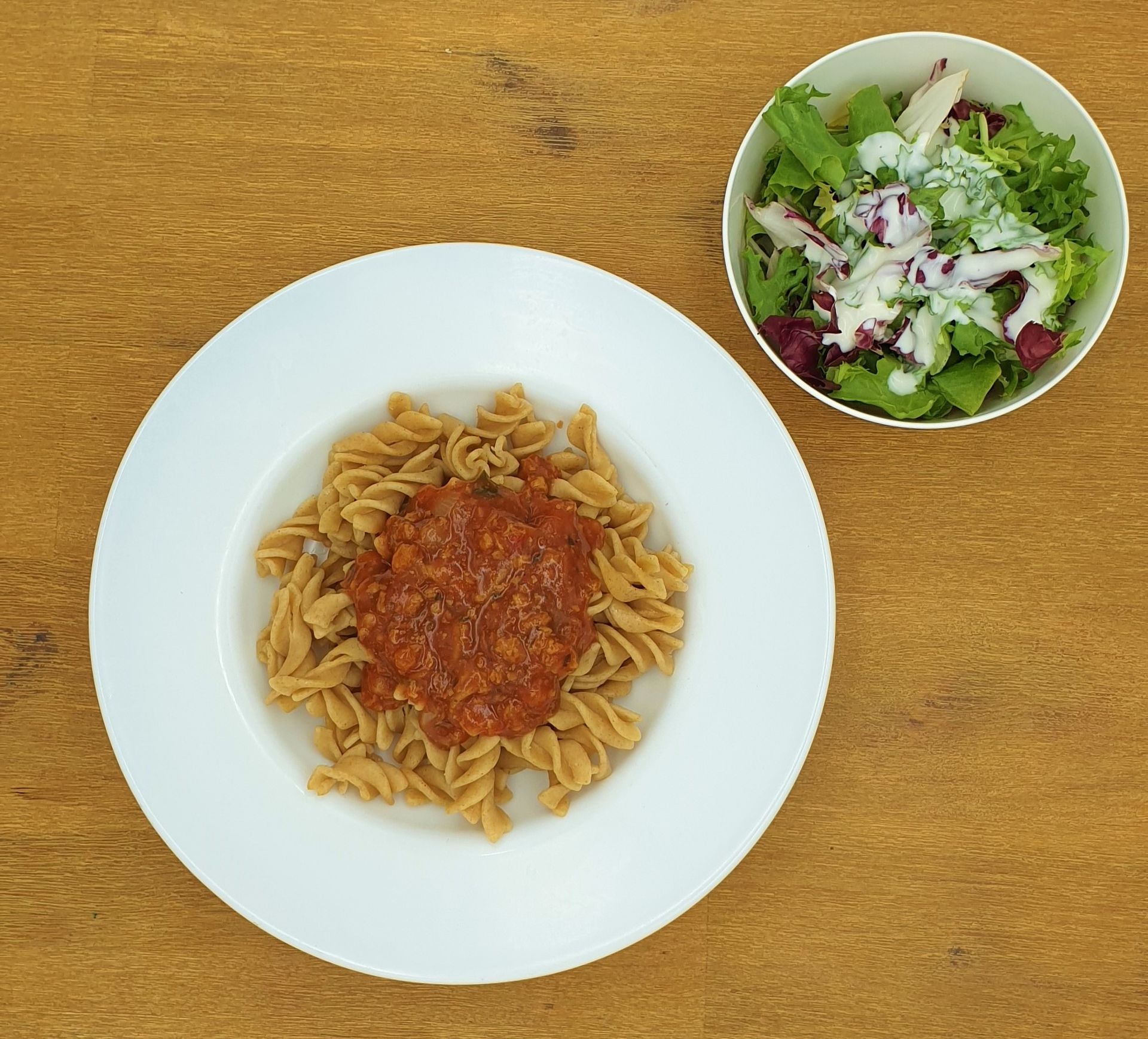 Auf einem weißen Teller mit Apfelmus lagen Crêpes auf einem Holztisch.