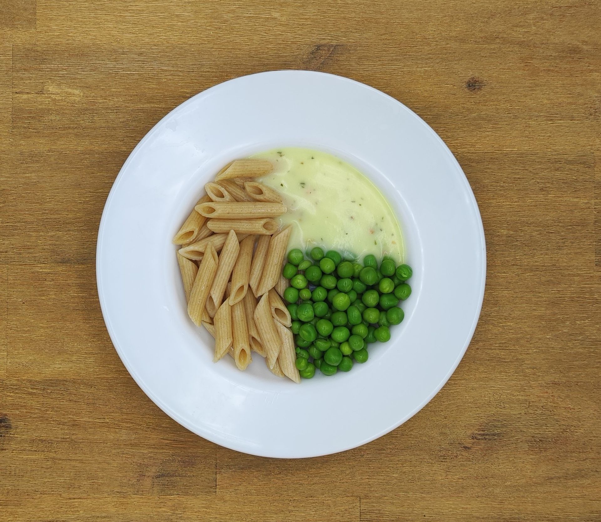 Ein Teller mit Essen, in drei Teile geteilt: Nudeln, Kartoffelpüree und Erbsen.