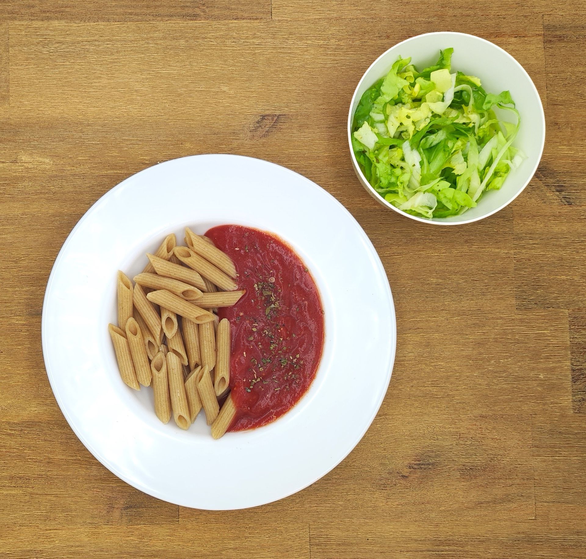Weiße Schüssel mit Linsensuppe und Brot auf einer Holzoberfläche.