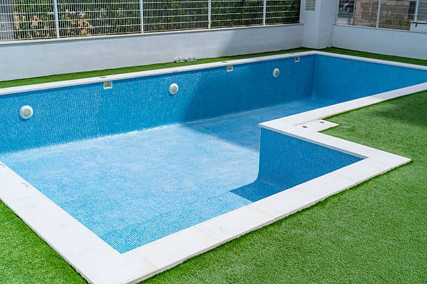 Empty, clean inground pool with blue tiles.