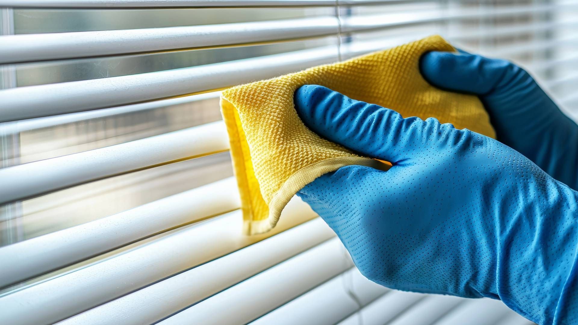 Someone cleaning their blinds with a cloth at Awnings, Blinds, & Shutters near Turnersville, NJ