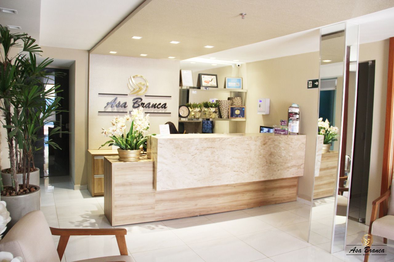 Um lobby de hotel com balcão de recepção e cadeirashotel-asa-branca