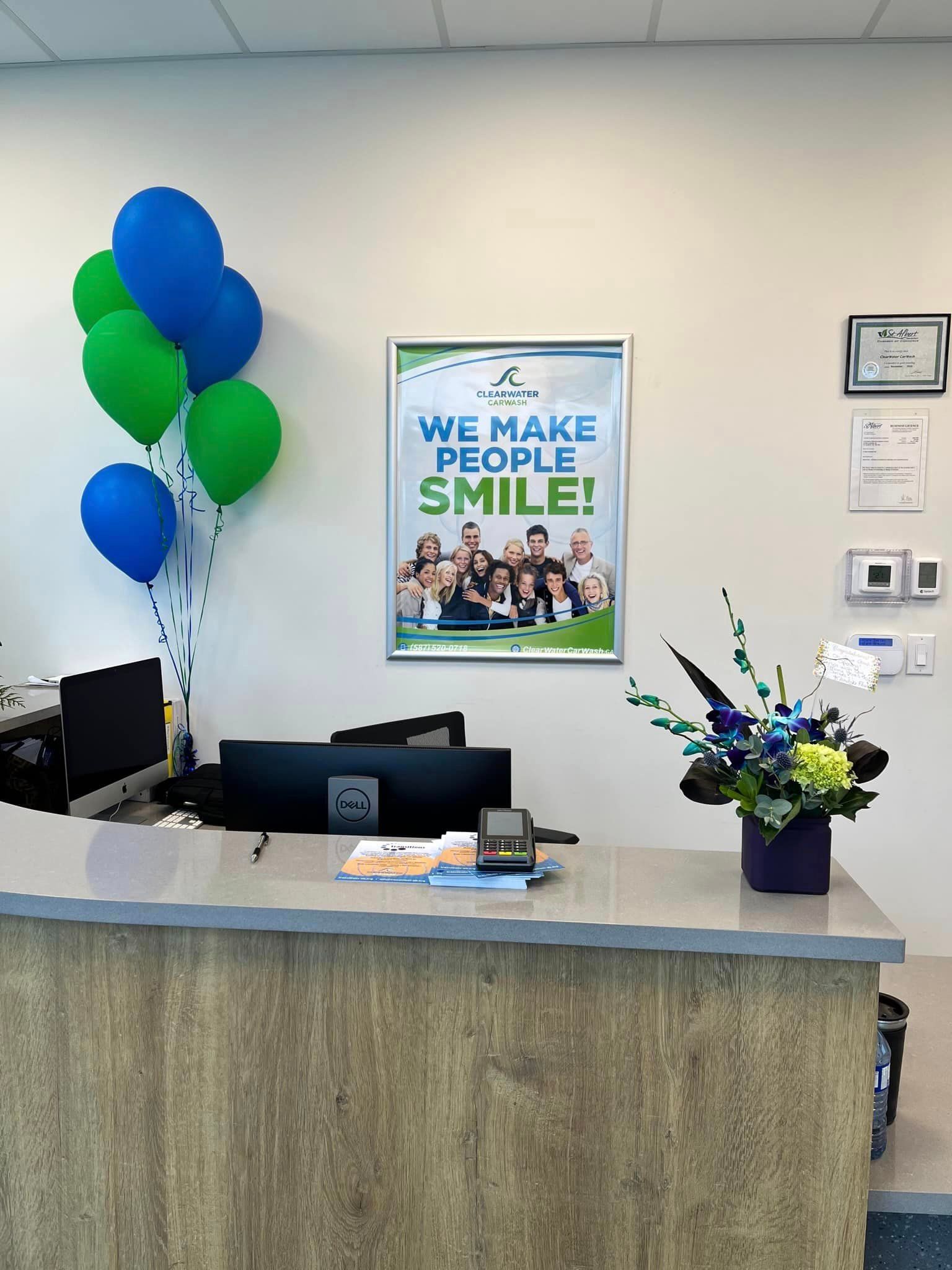 reception desk with balloons and flowers, poster on wall reads 