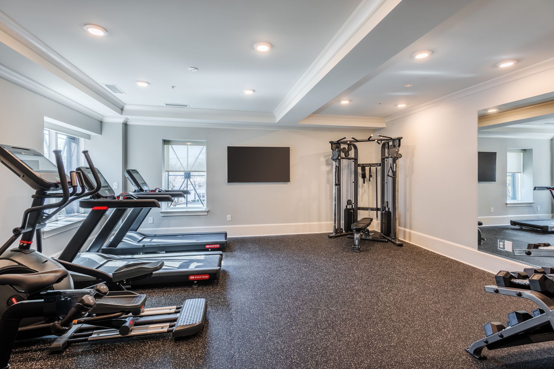 Gym interior with treadmills, weight machine, and large mirror.