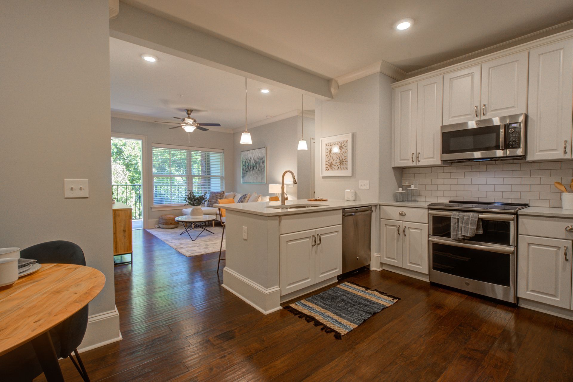 Kitchen with white cabinets, stainless steel appliances, and island with a view into the living room.