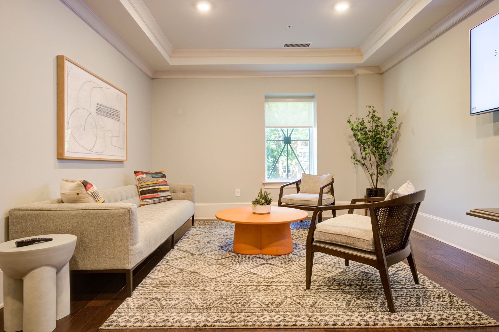 Living room with sofa, chairs, rug, and orange coffee table.