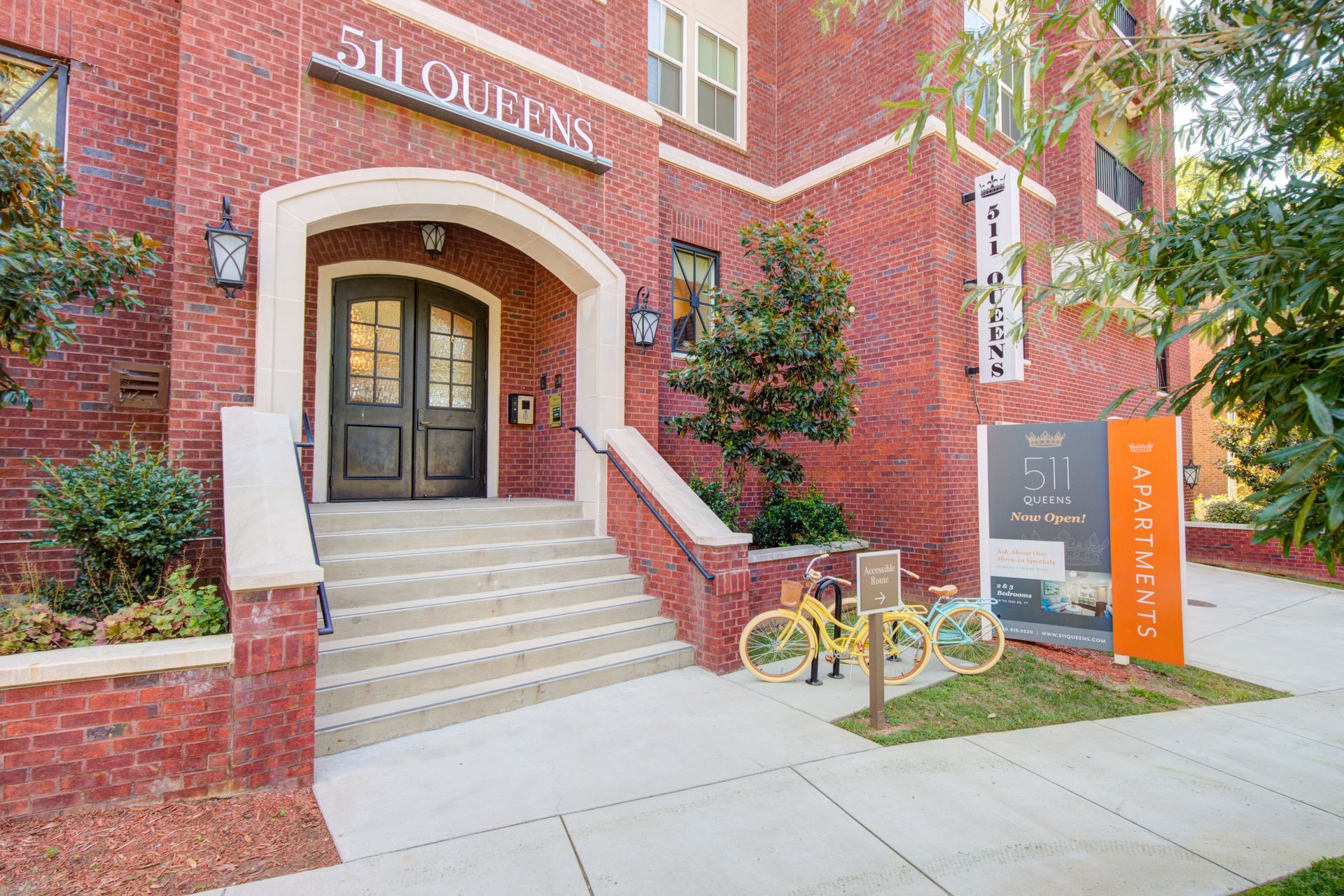 Entrance to 511 Queens apartments; red brick building with steps, double doors, and signage.