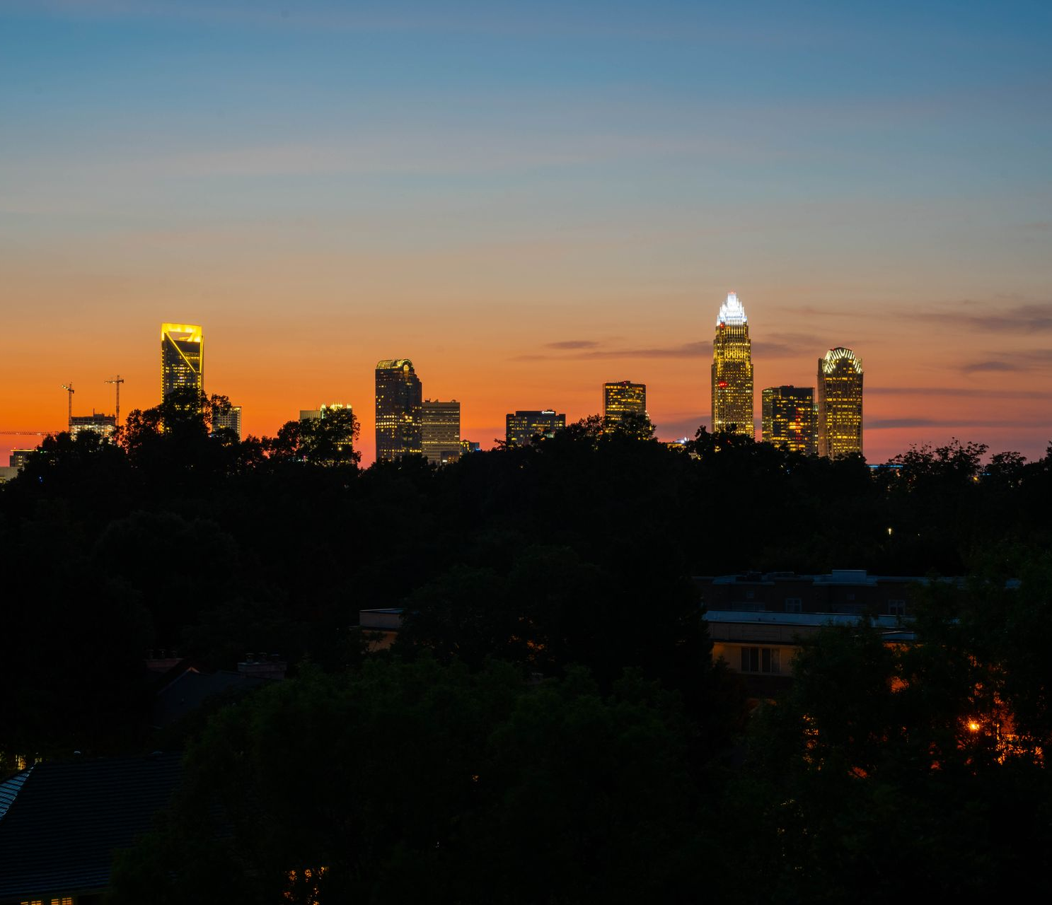 Charlotte, NC skyline silhouetted against an orange and blue sunset.