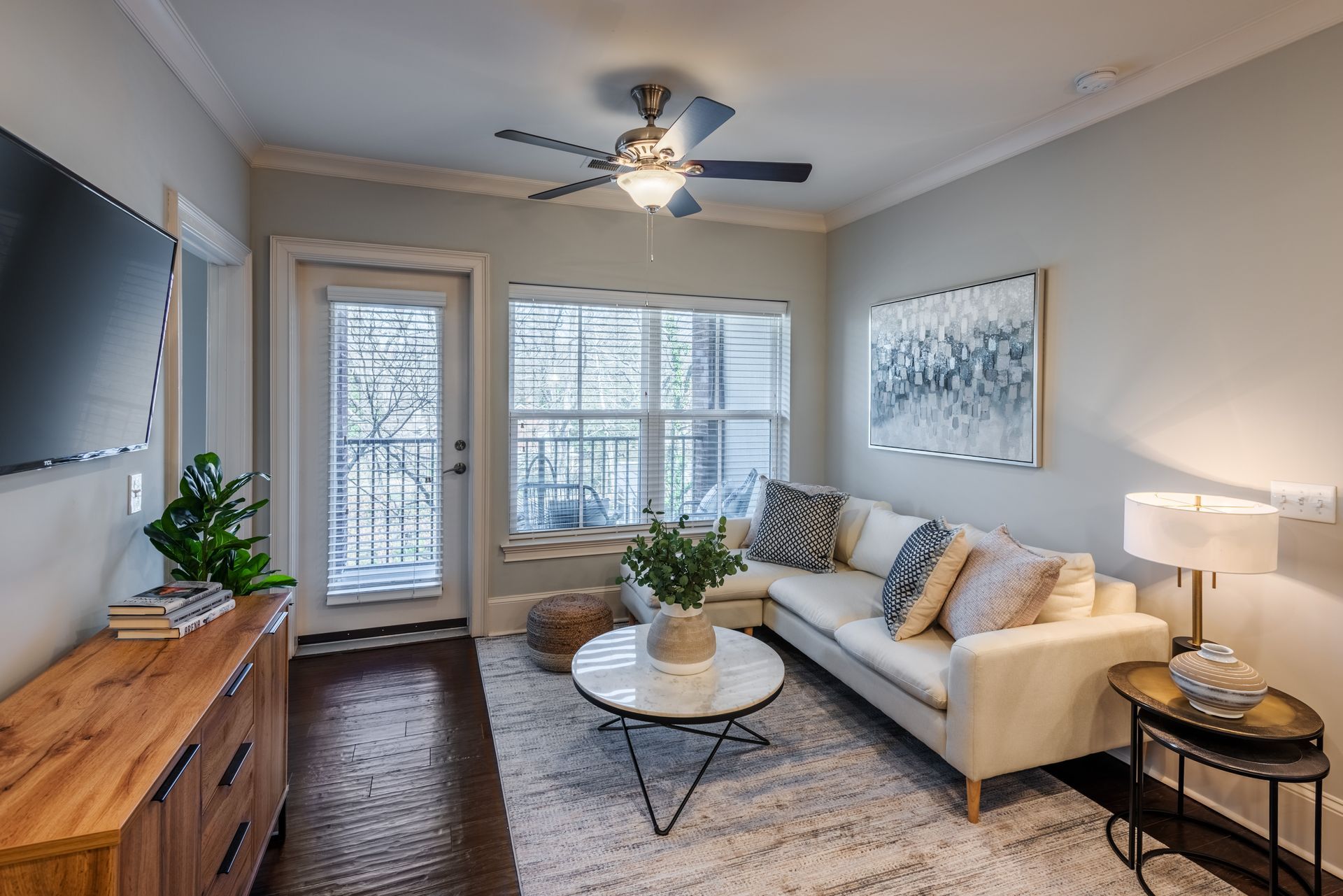 Living room with white sectional, wood console, and balcony access.