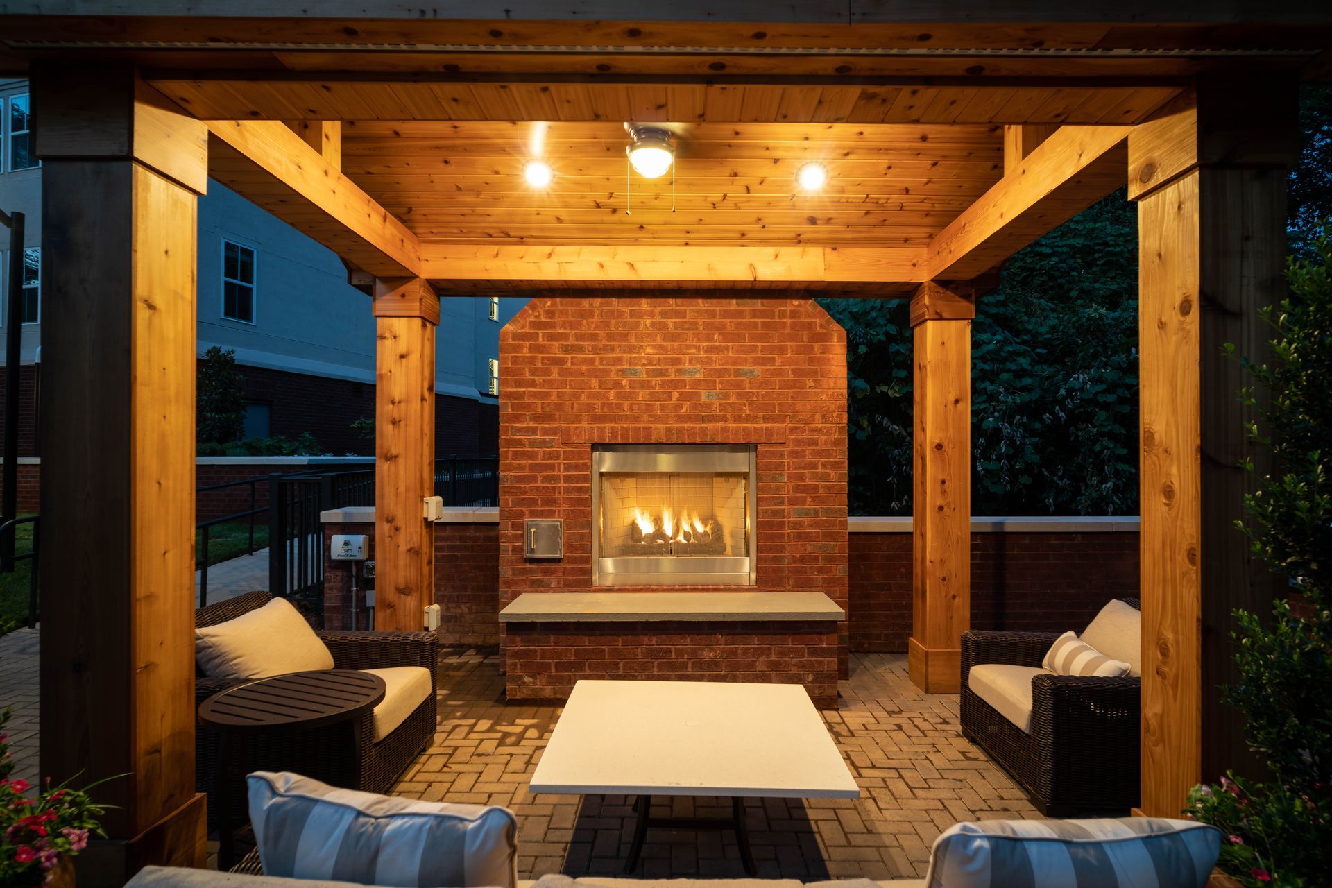 Outdoor patio with a brick fireplace, seating, and overhead lights.