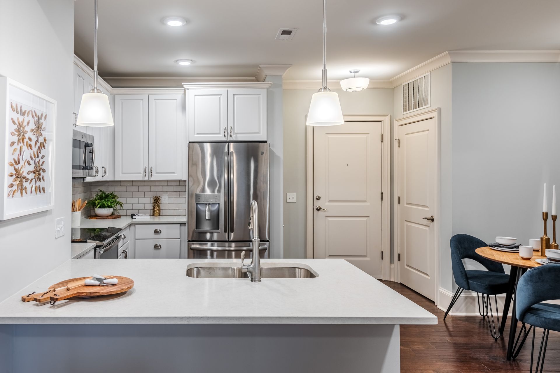 Bright kitchen with white cabinets, stainless steel appliances, and a quartz countertop island.