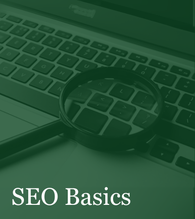 A magnifying glass sits on top of a laptop keyboard with the words seo basics below it