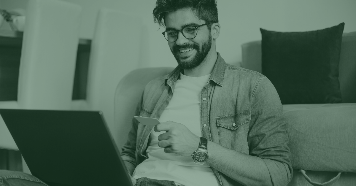 A man is sitting on a couch using a laptop computer.