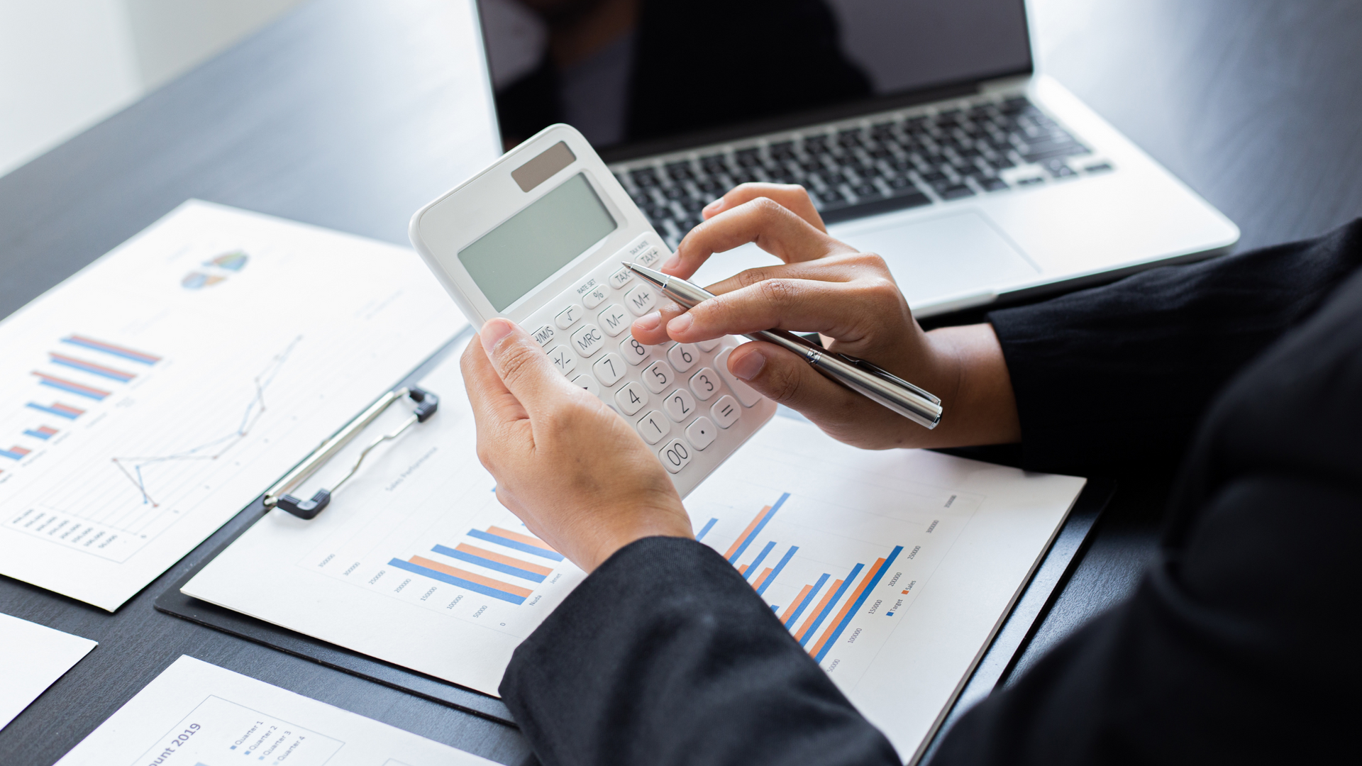 Image of somebody calculating revenue on a calculator.