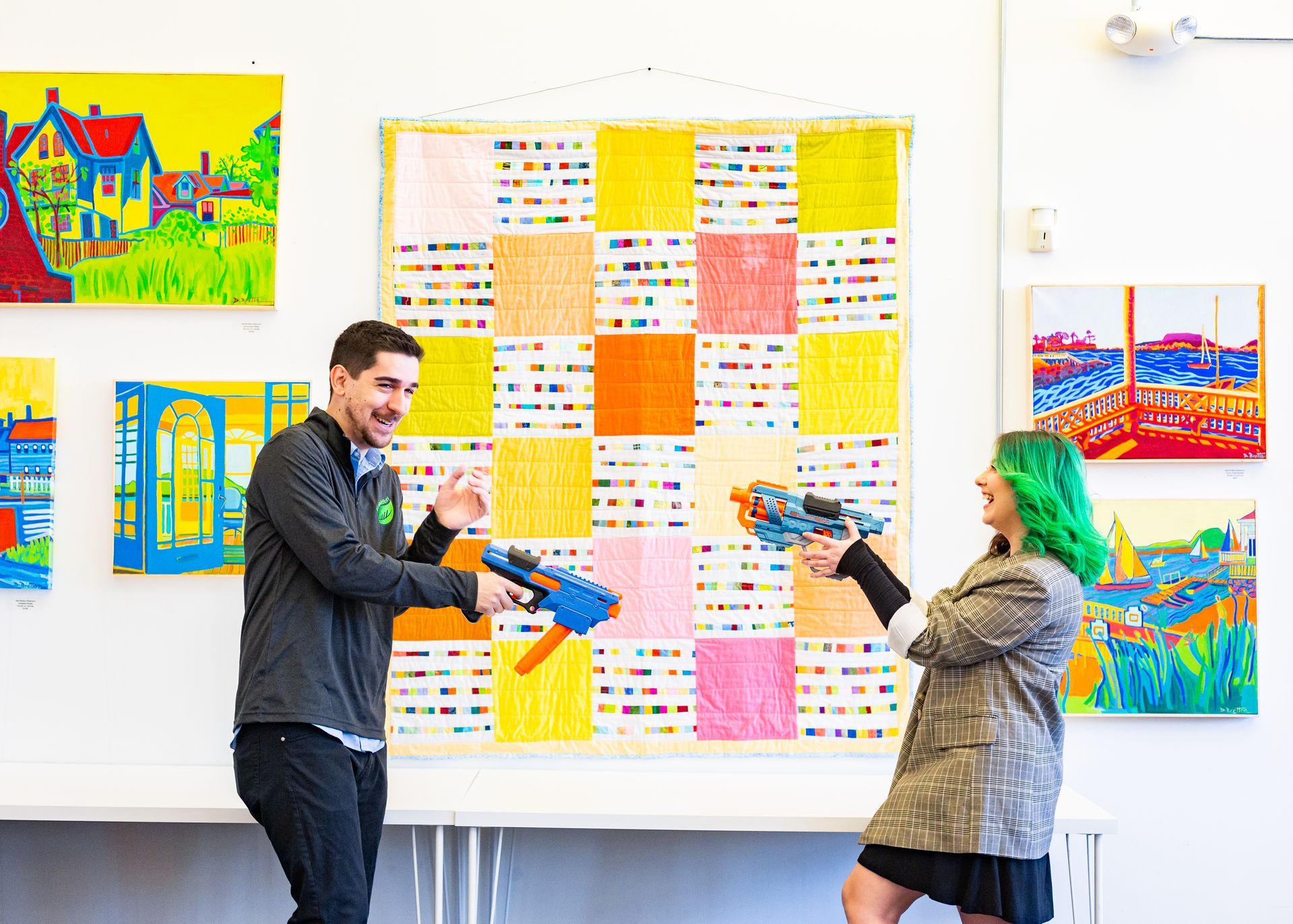 A woman and a man holding Nerf guns at each other