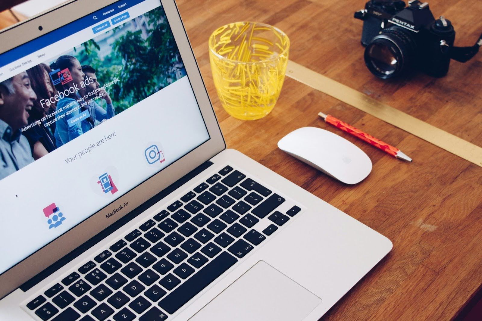 A laptop computer is open to a facebook page on a wooden table.