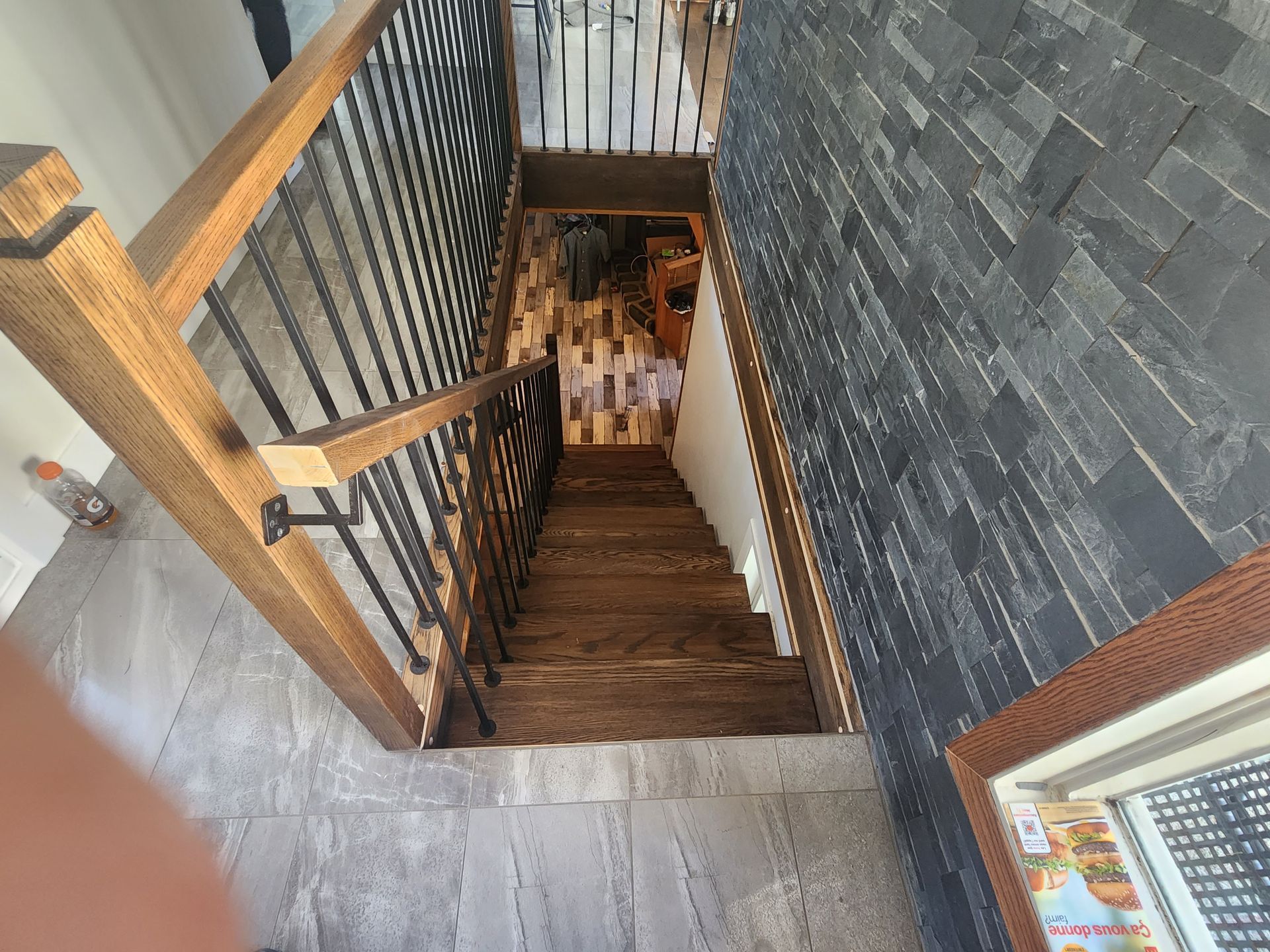 Une vue aérienne d'un escalier en bois avec une rampe en métal et un mur en pierre.