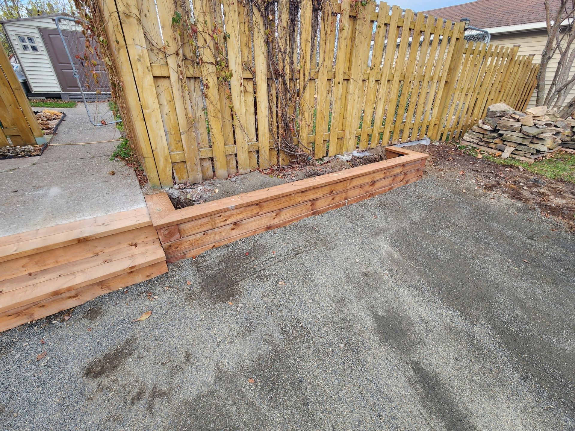 Il y a une clôture en bois en arrière-plan et un mur en bois au premier plan.