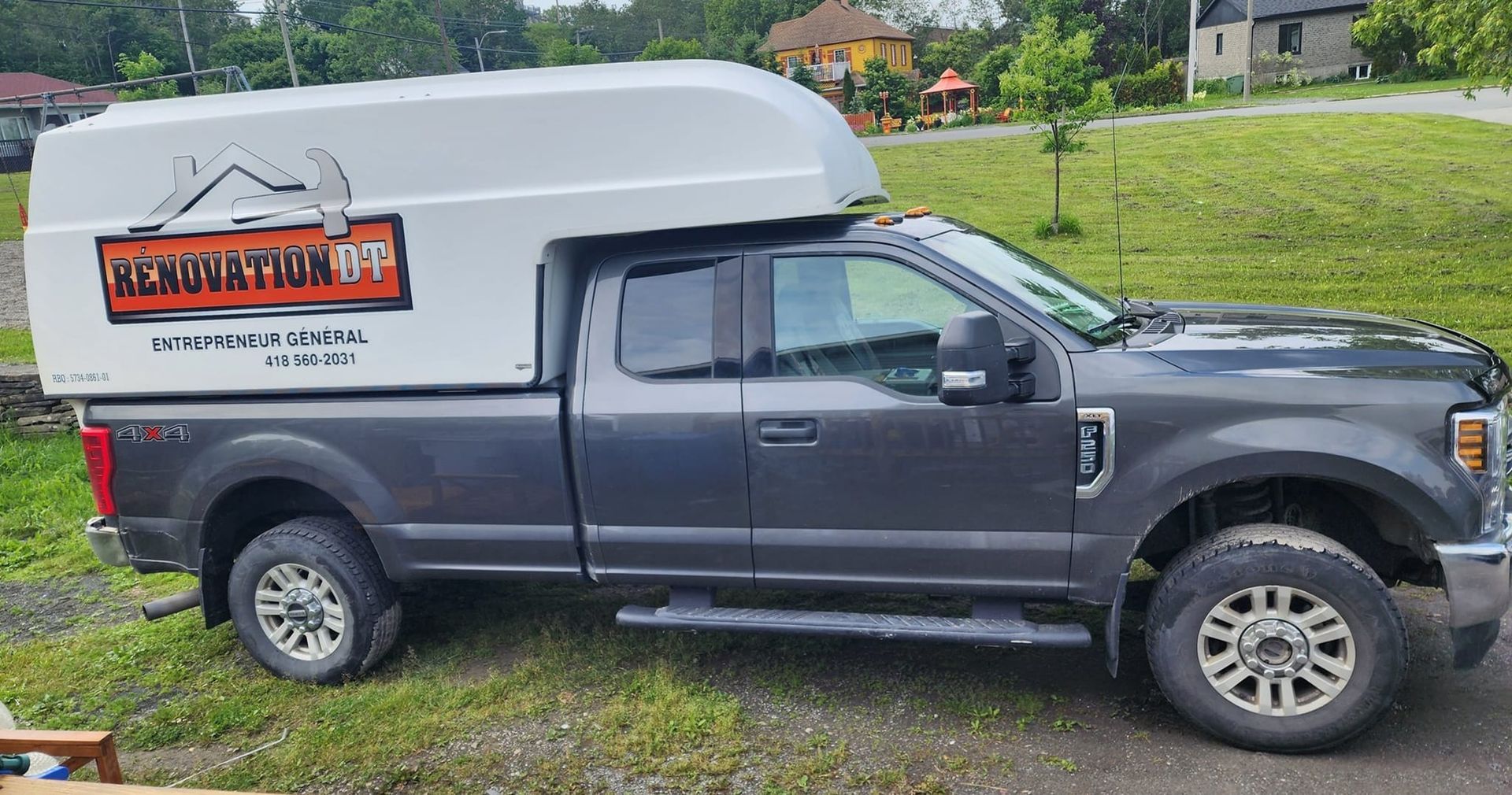 Un camion gris avec un auvent blanc est garé sur le bord de la route.