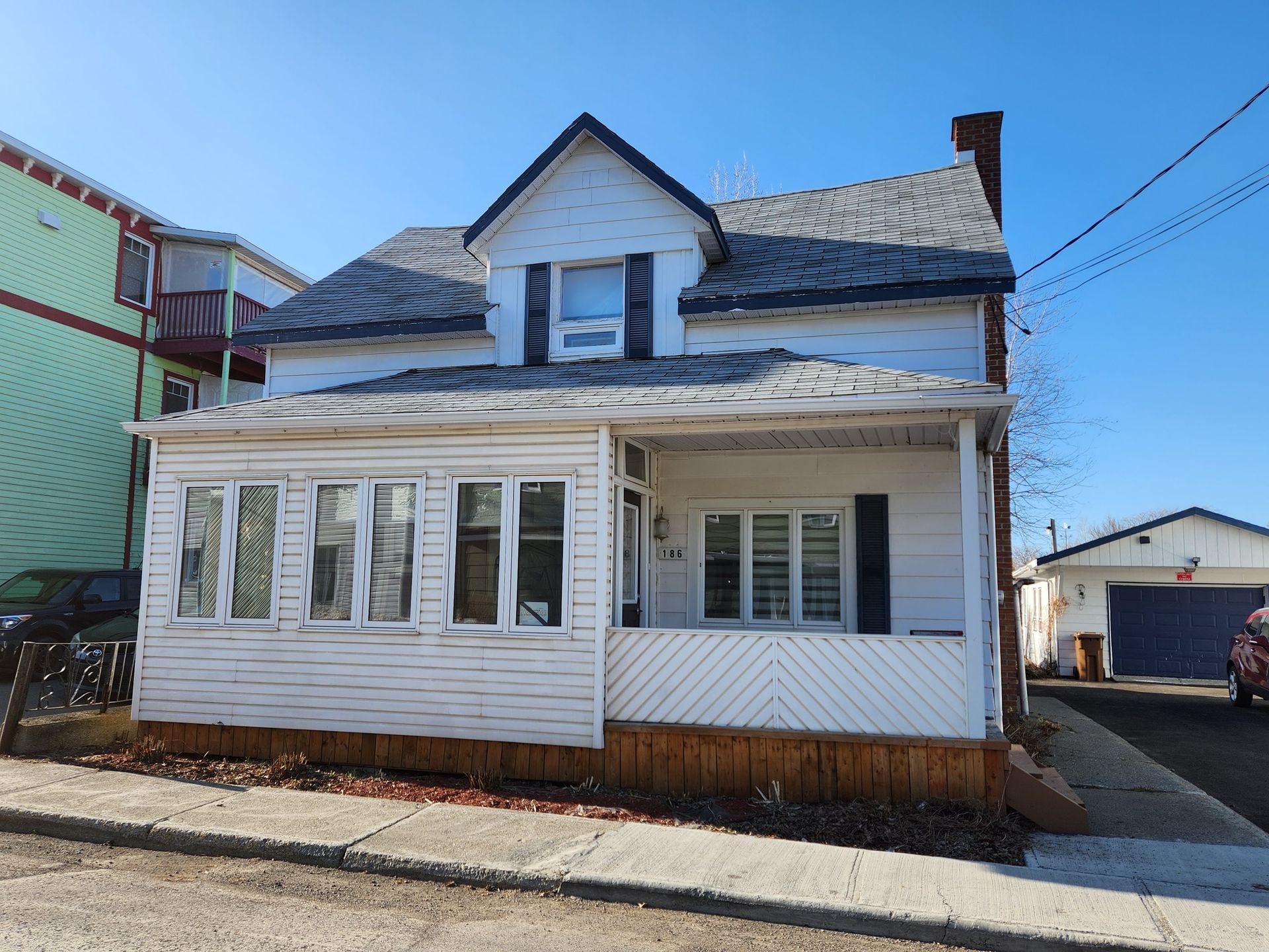 Une maison blanche avec un porche et un ciel bleu en arrière-plan