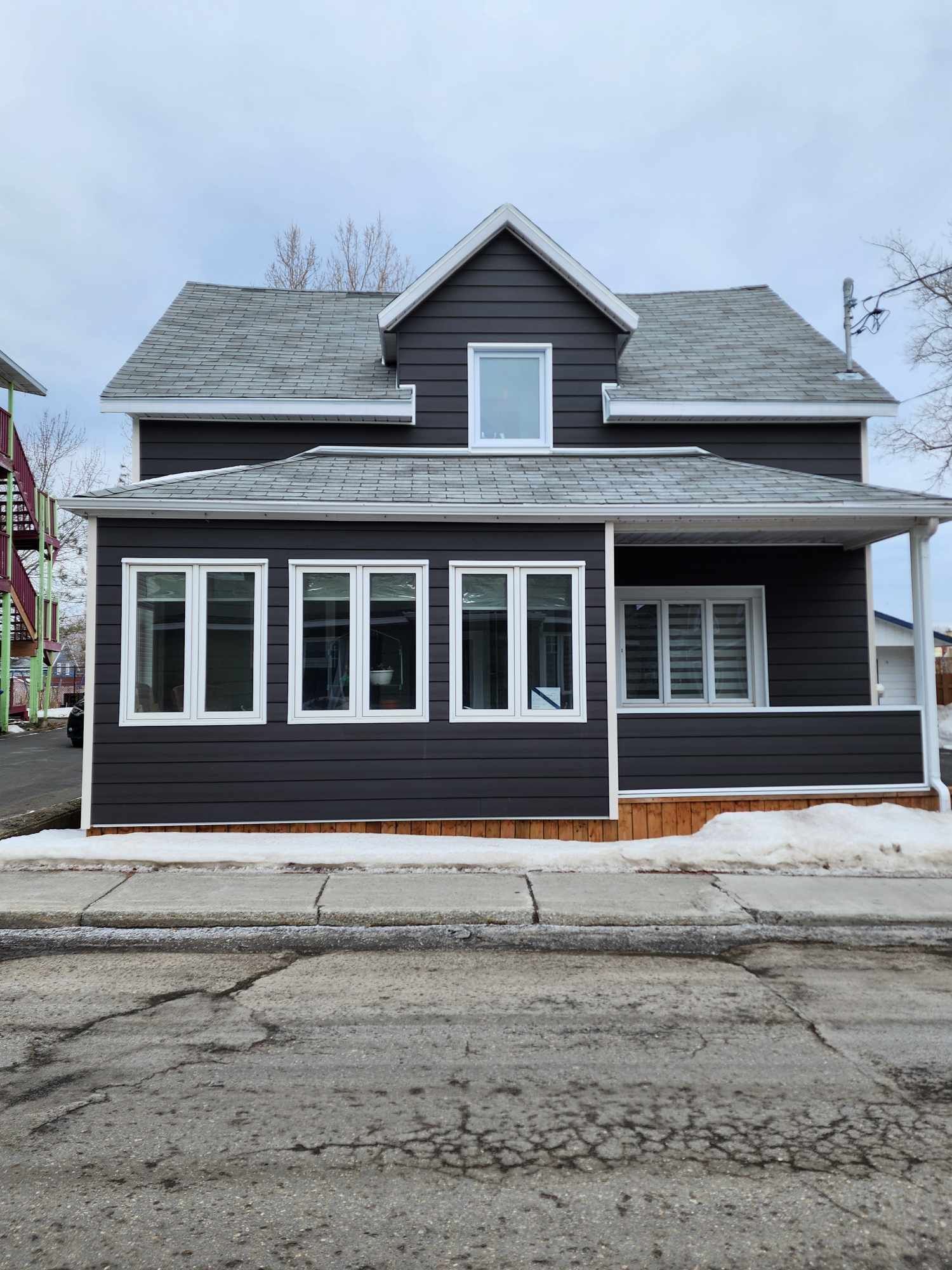 Une grande maison avec beaucoup de fenêtres se trouve au bord de la route.