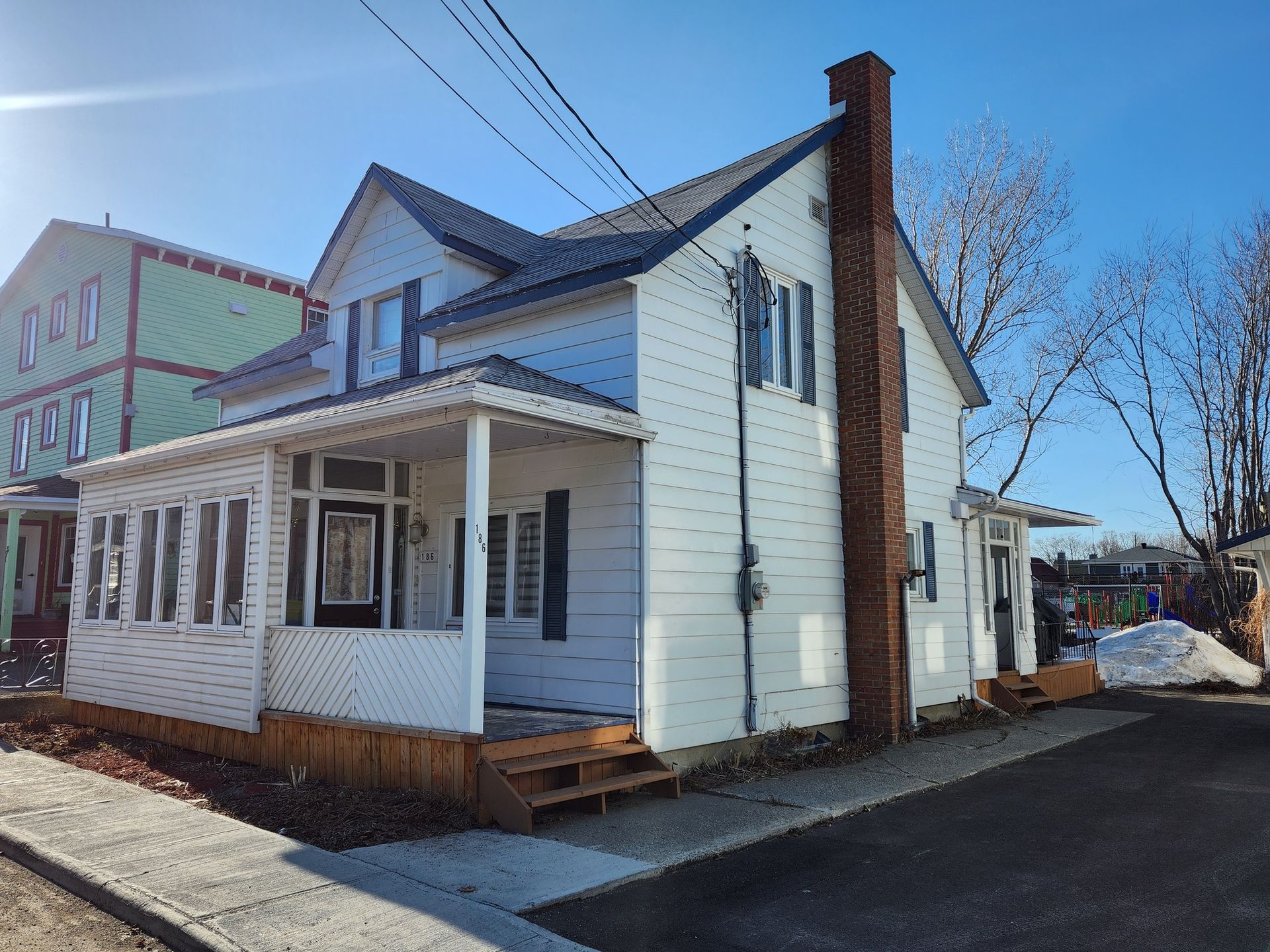 Une maison blanche avec une cheminée en brique sur le côté