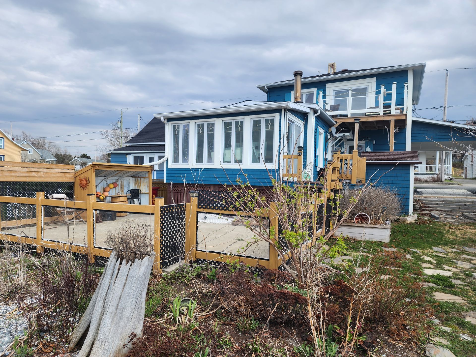 Une maison bleue et blanche avec une clôture en bois devant.