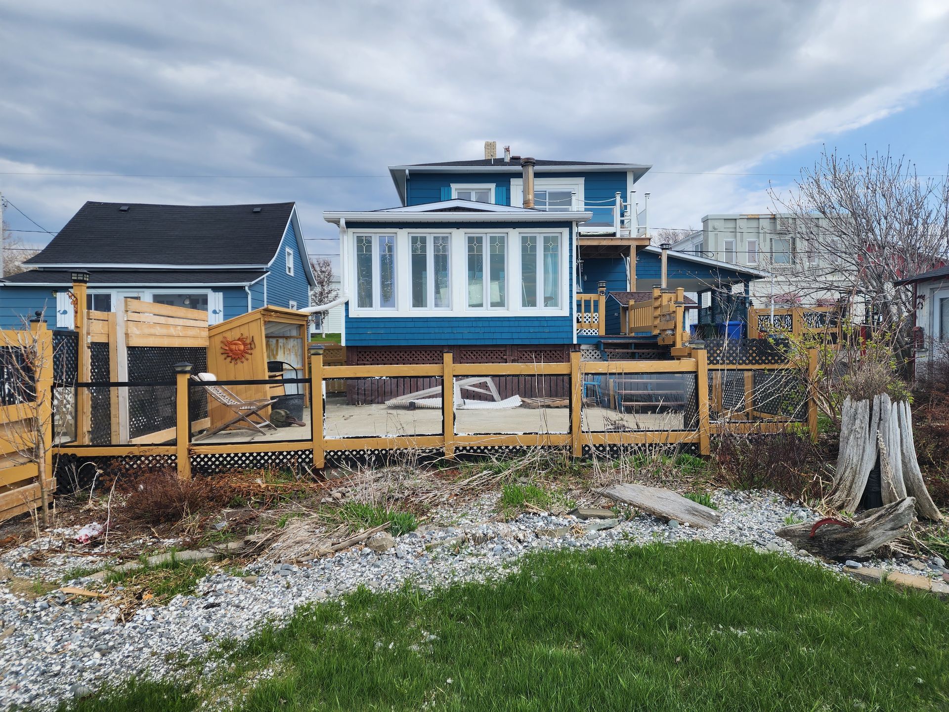 Une maison bleue et blanche avec une clôture en bois devant.