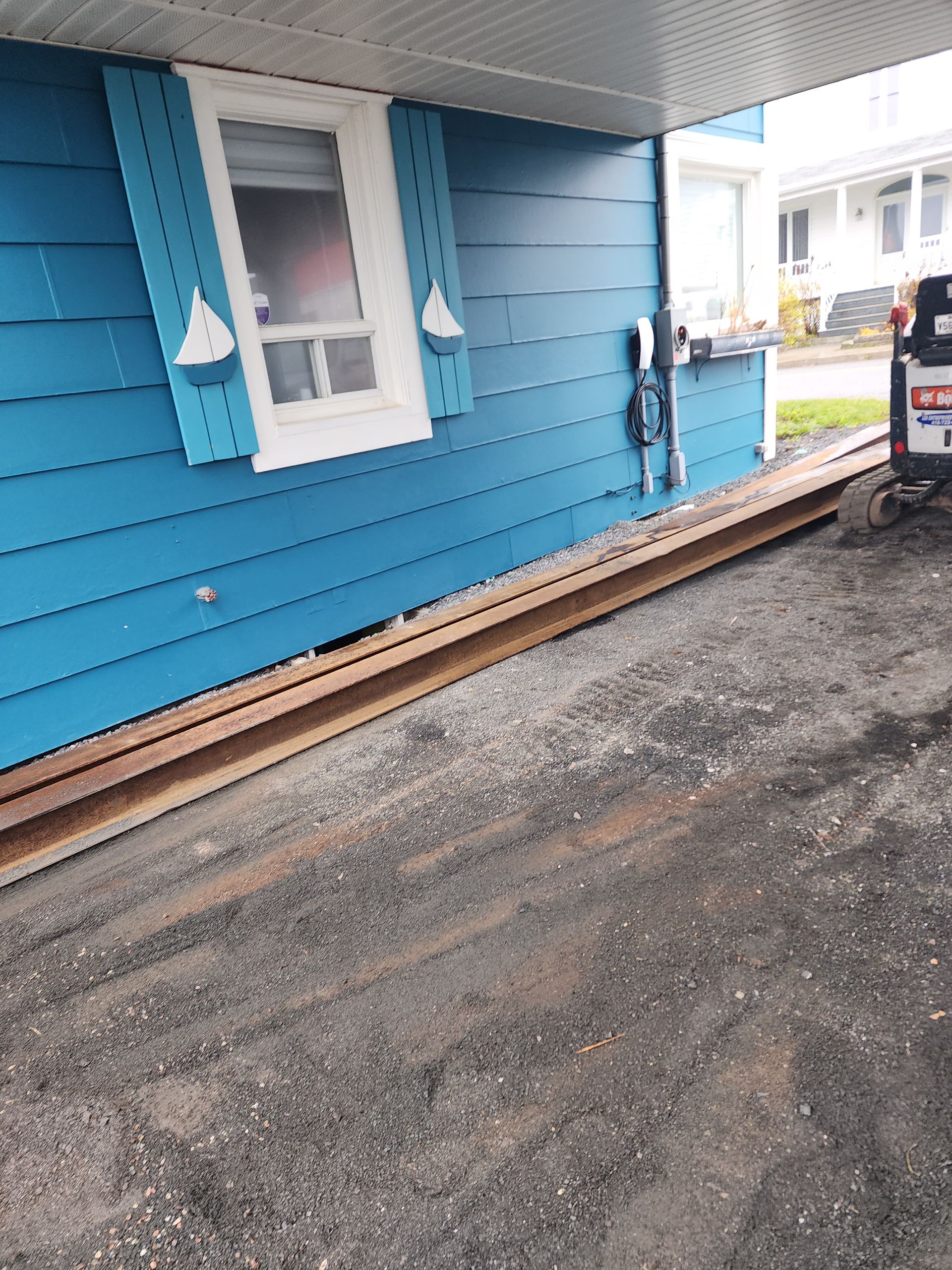 Une maison bleue est déplacée par un bulldozer.