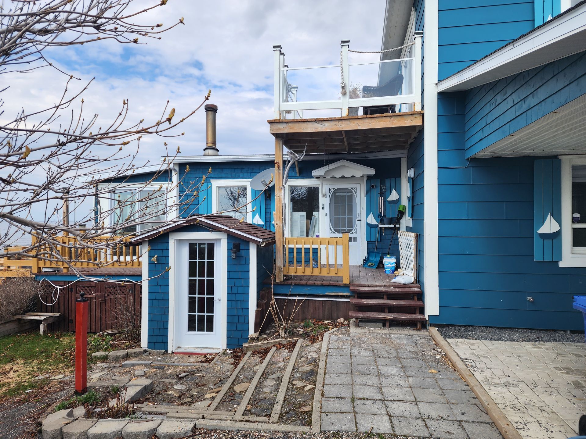 Une maison bleue avec un hangar devant