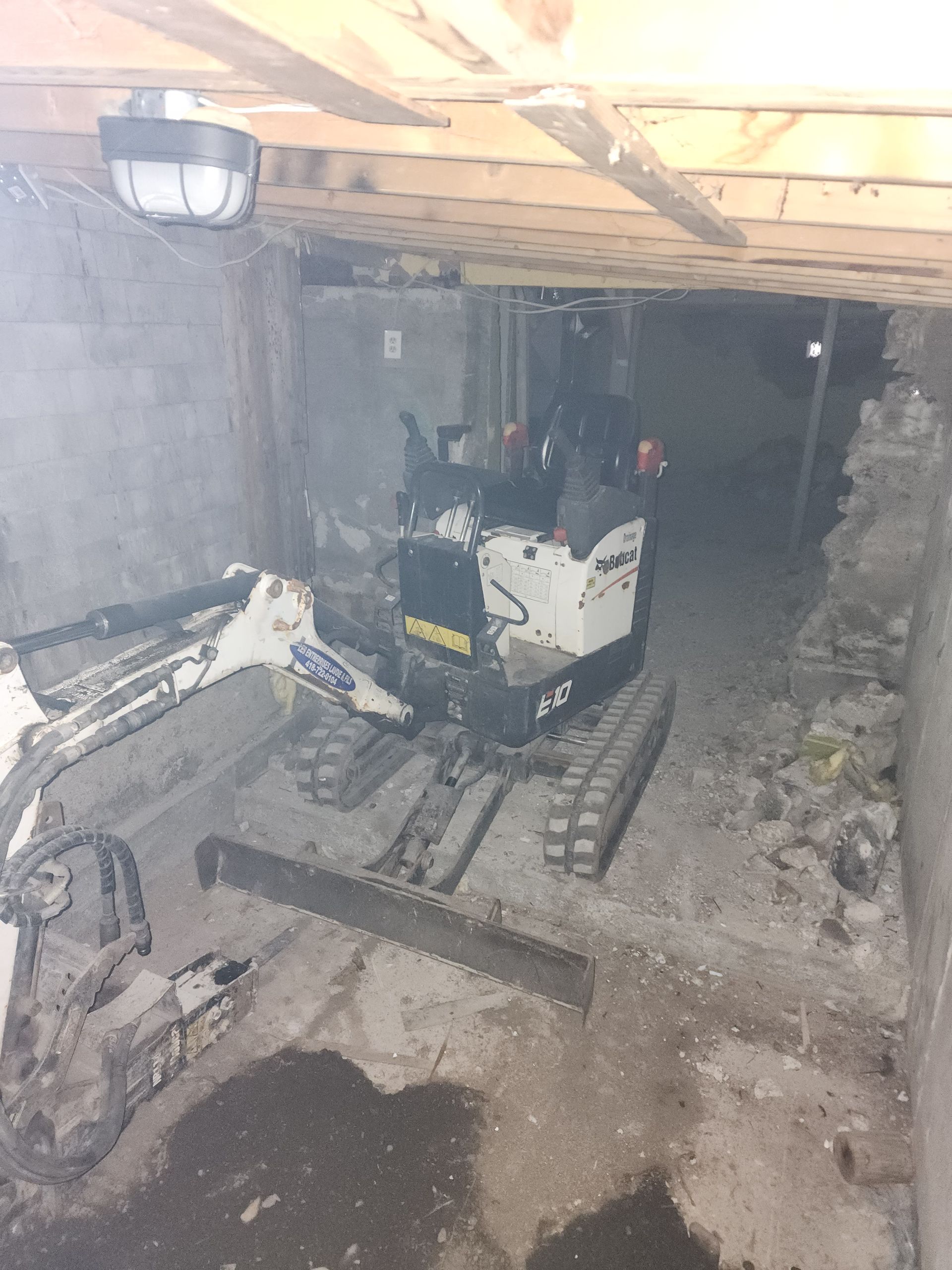 Une petite excavatrice se trouve dans un sous-sol sombre.